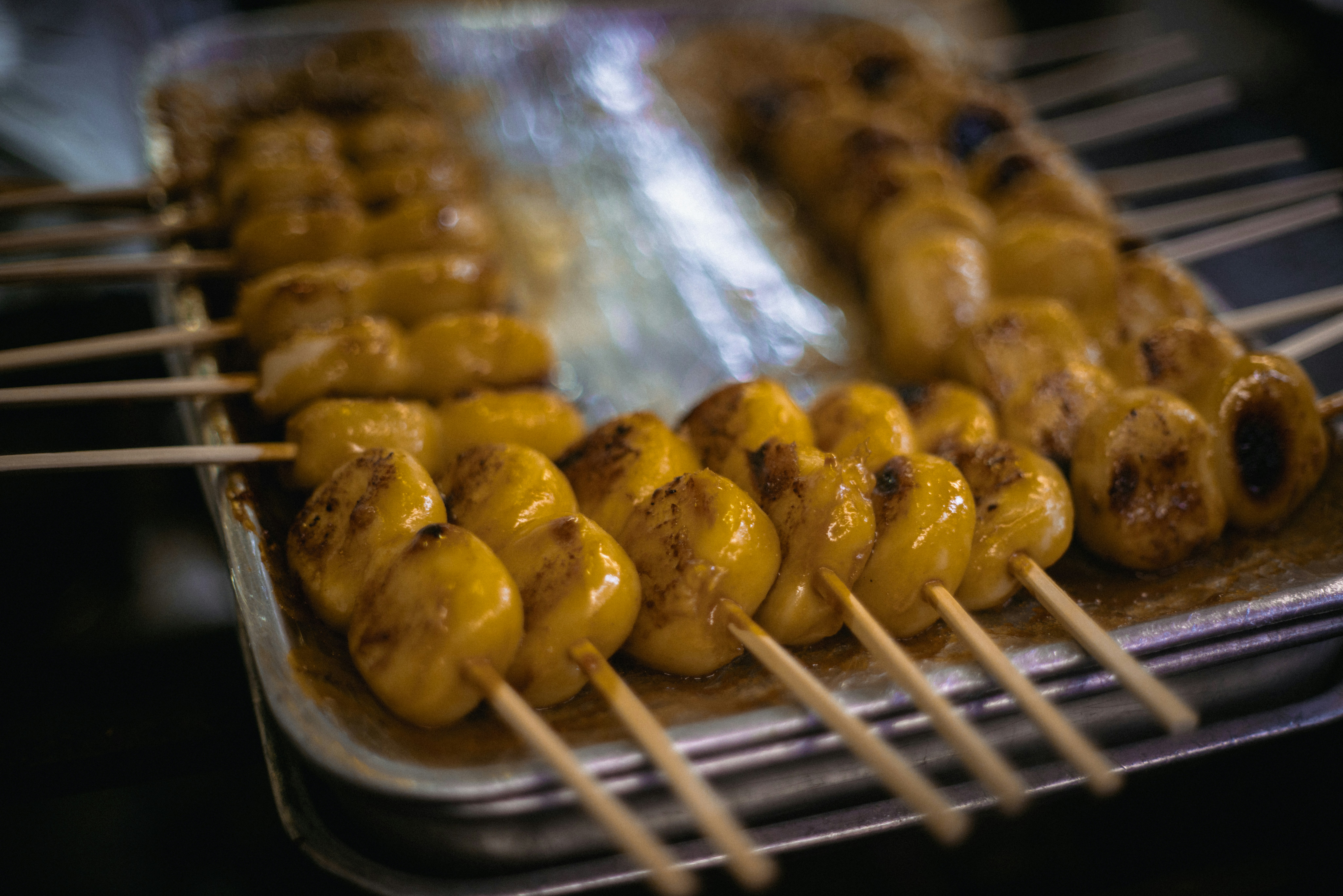 Grilled skewers of yellow mochi on a tray