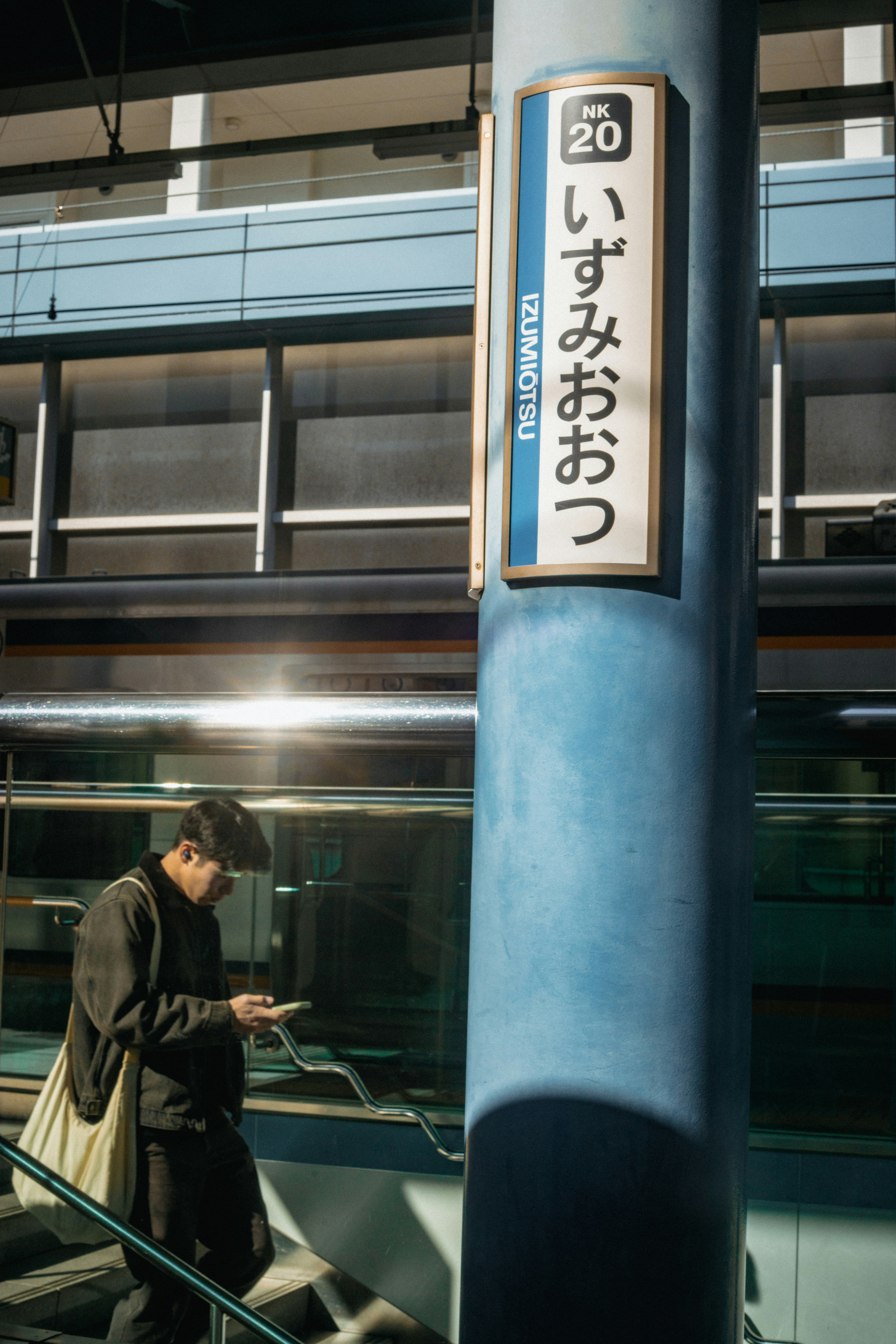 Man looking at phone on train station stairs