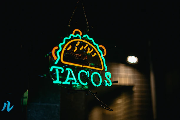 A neon sign advertising tacos at night