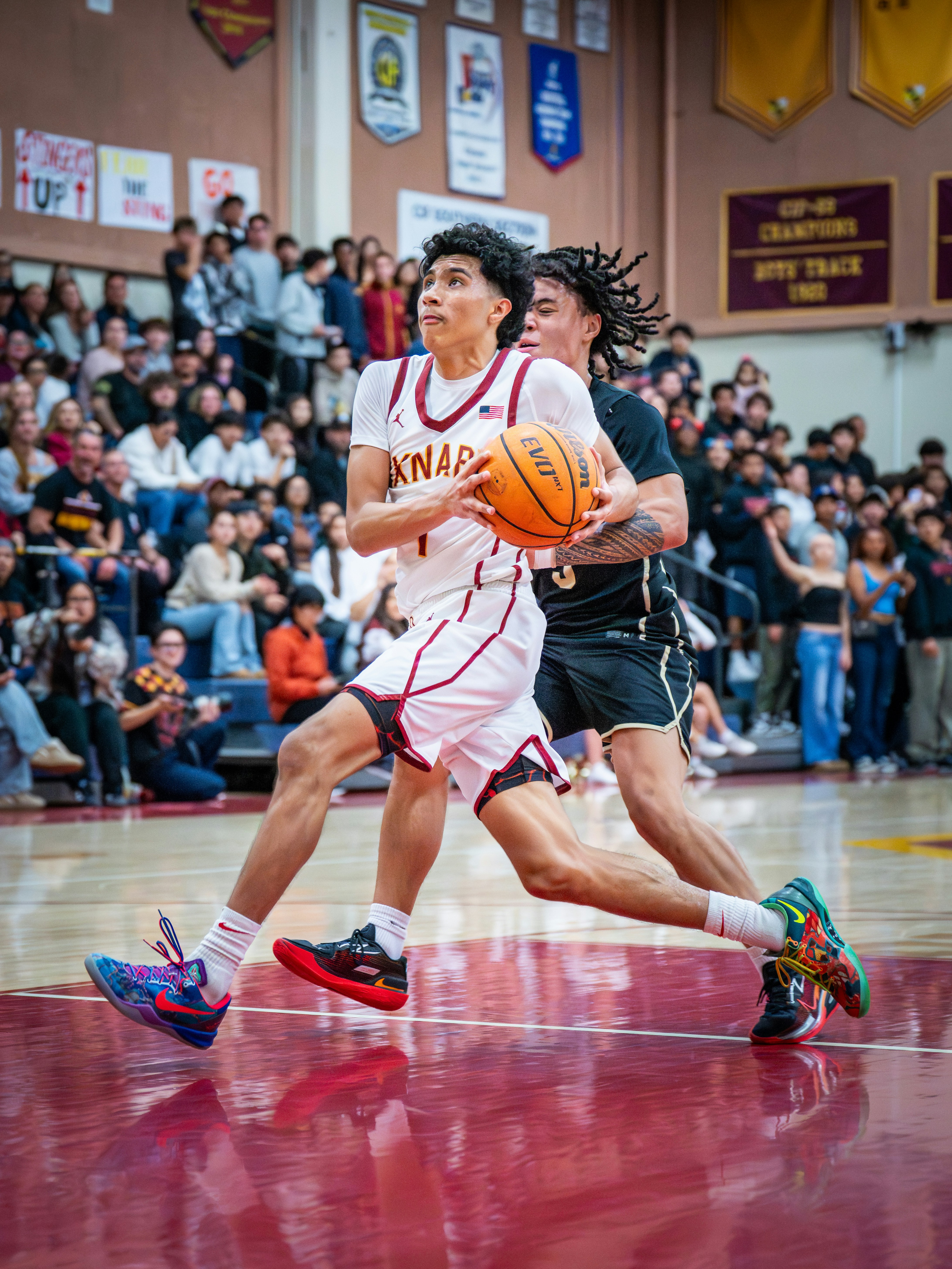 Basketball player dribbles past defender during a game.