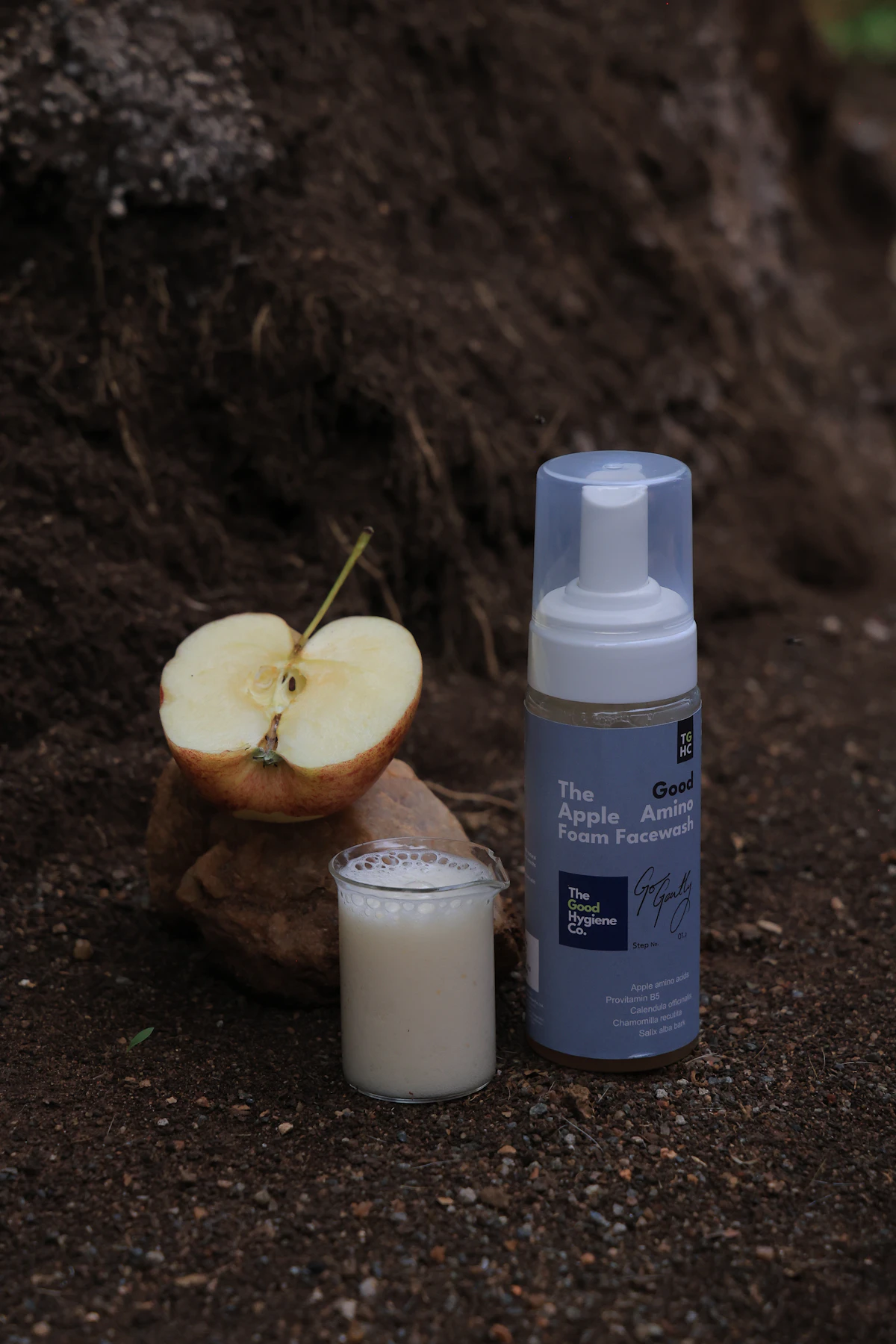 A dollop of creamy foam cleanser styled next to a fresh apple on a light textured surface