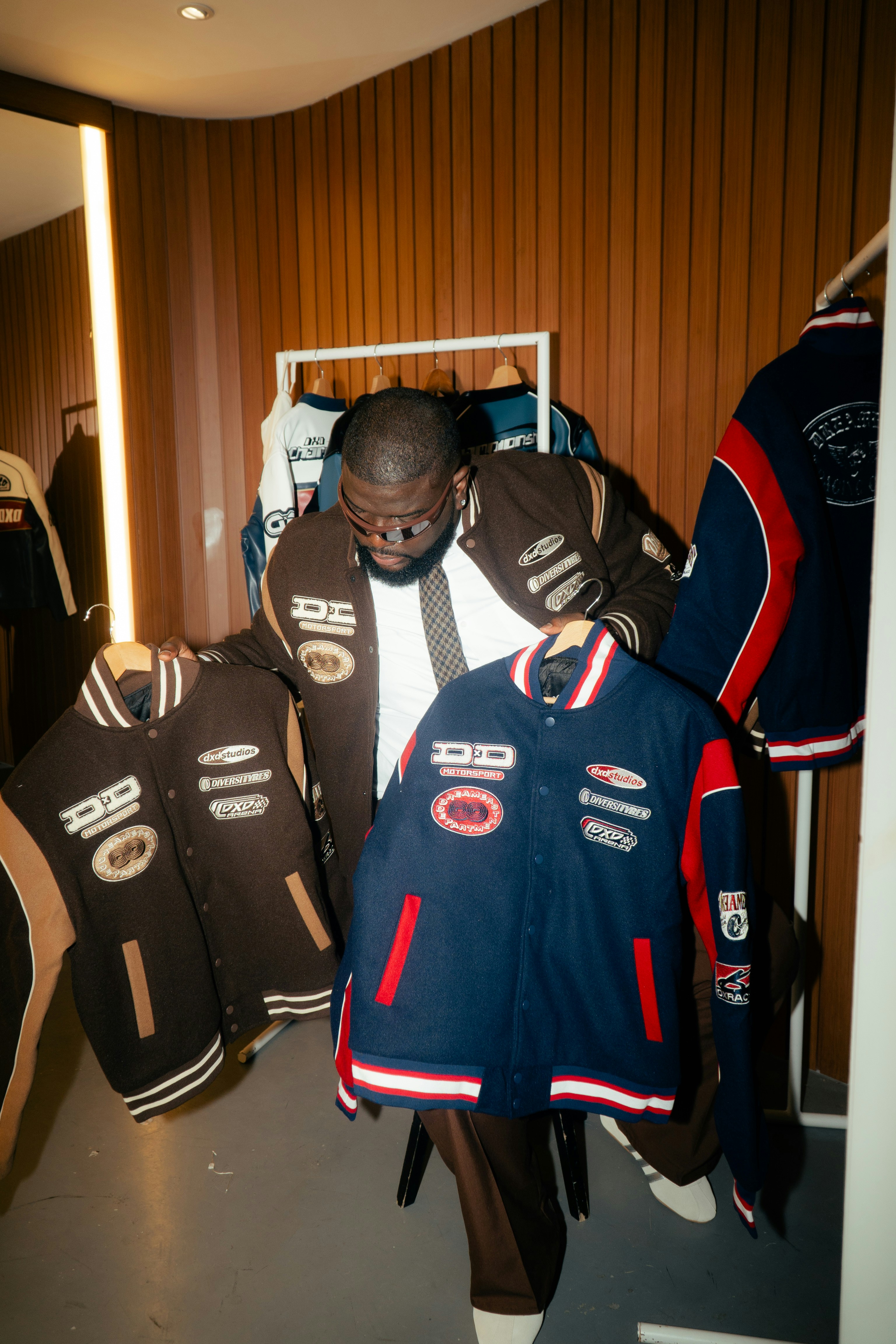 Man holding varsity jackets in a store