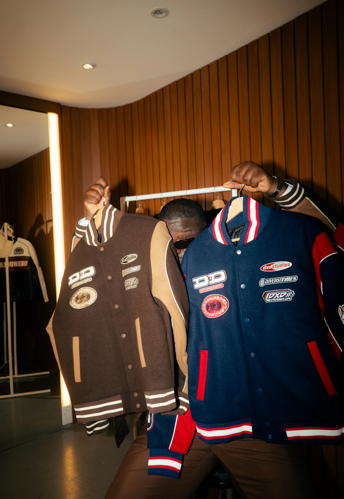 Two finished custom varsity jackets in brown and blue held up after production