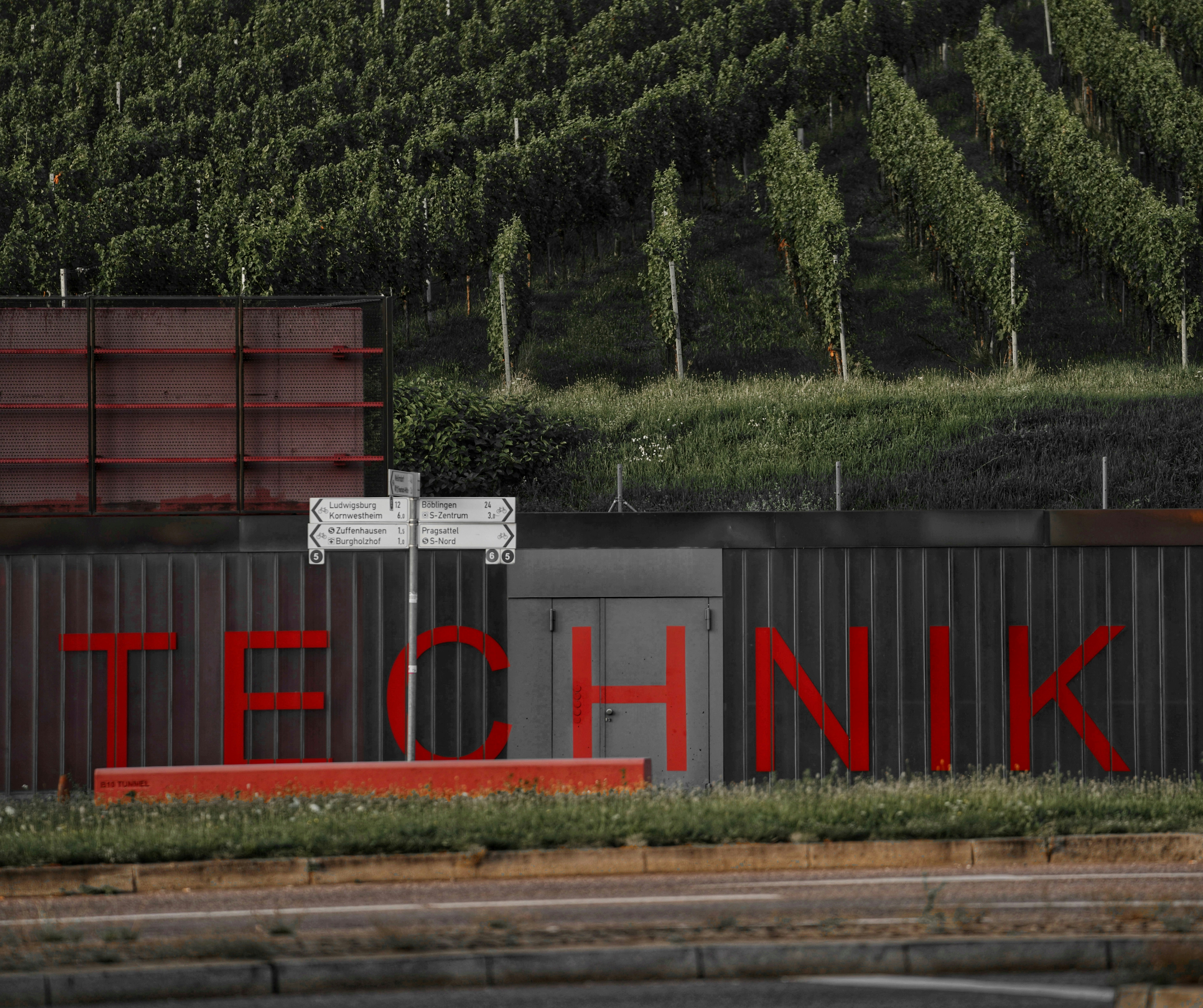 Red lettering spells out technik on a corrugated metal wall.