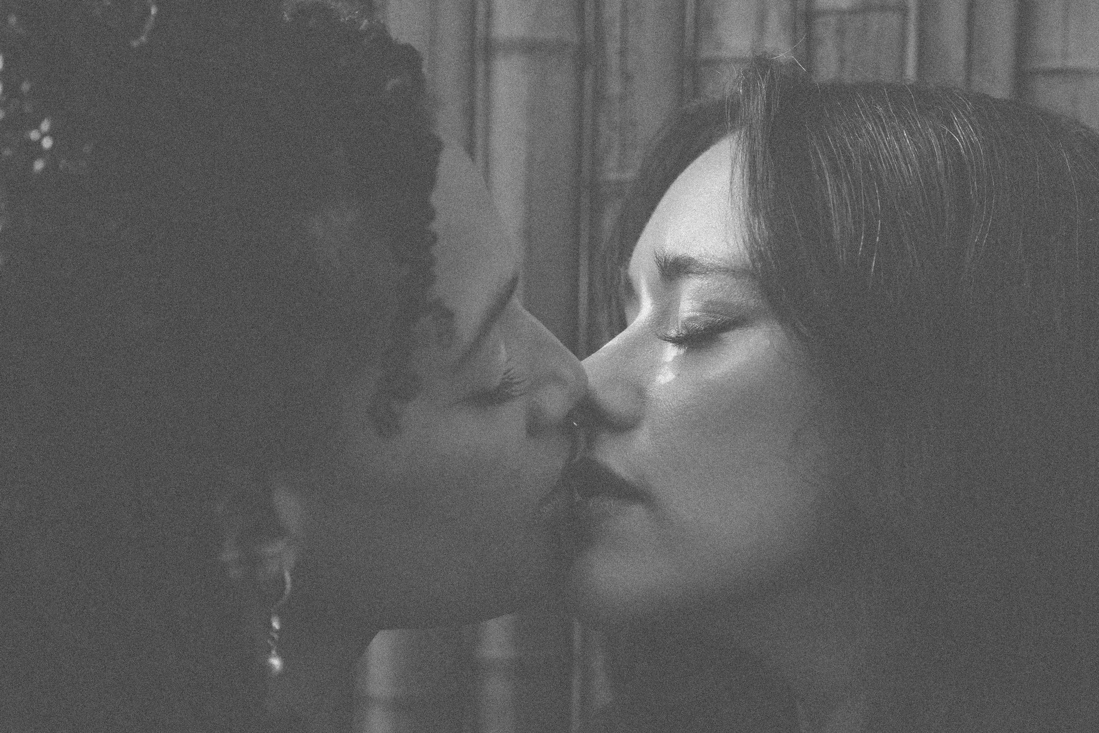 Two women kissing passionately in black and white.