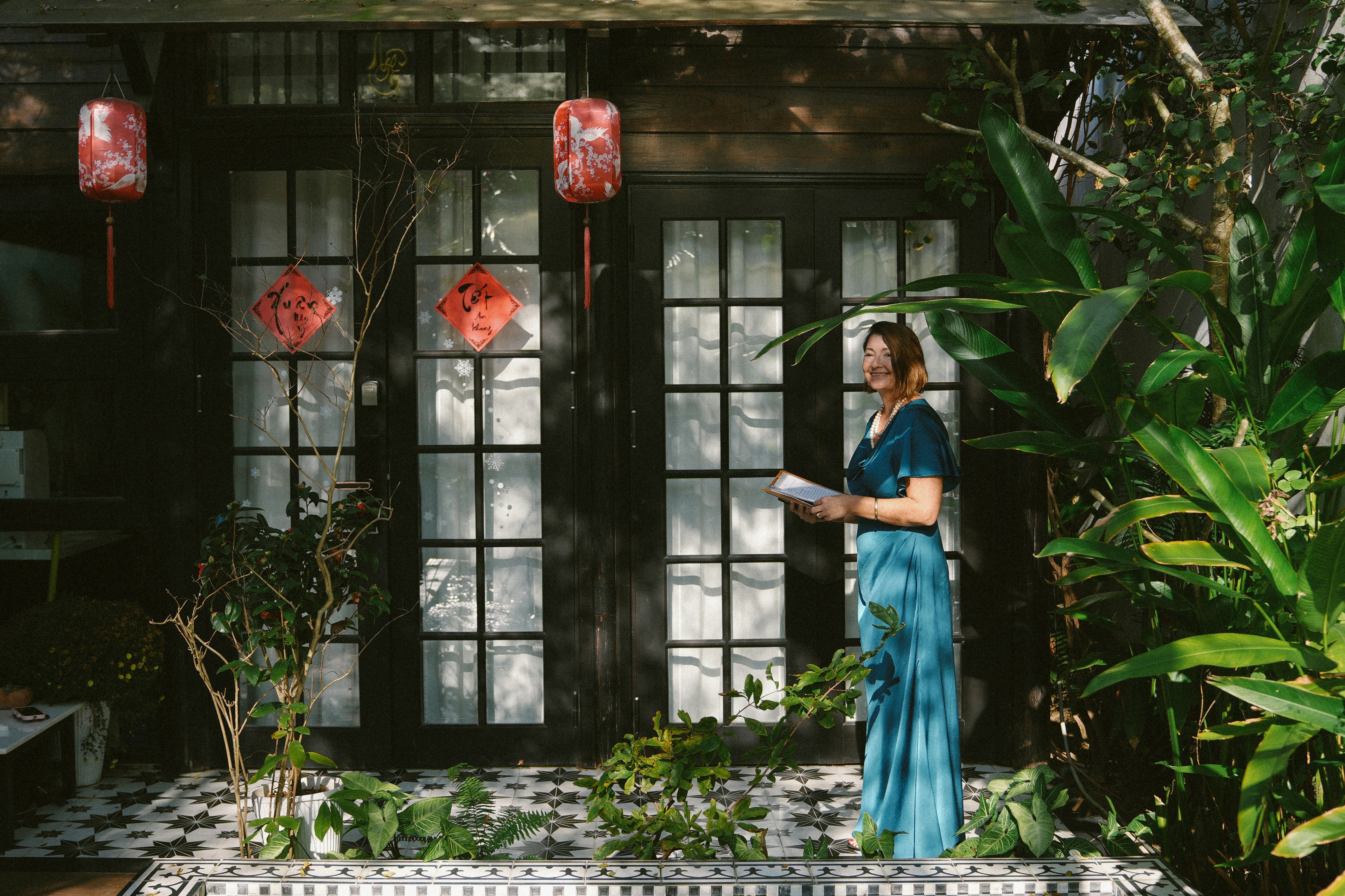 Donna in abito blu in piedi vicino a una casa con lanterne.