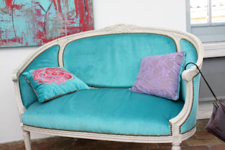 A vintage teal sofa with decorative pillows.