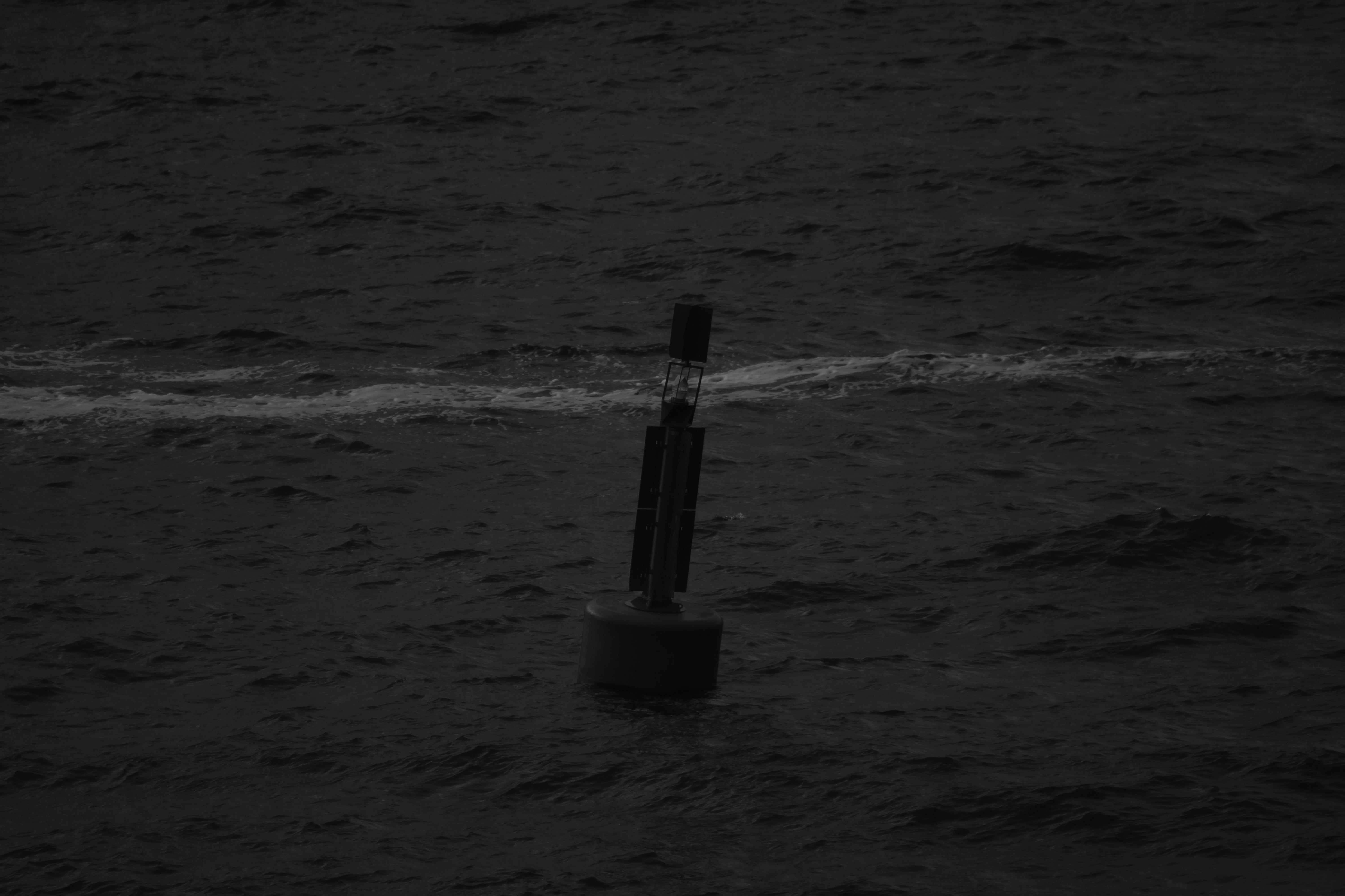 Eine einzelne Boje treibt auf dunklem, kräuselndem Wasser.