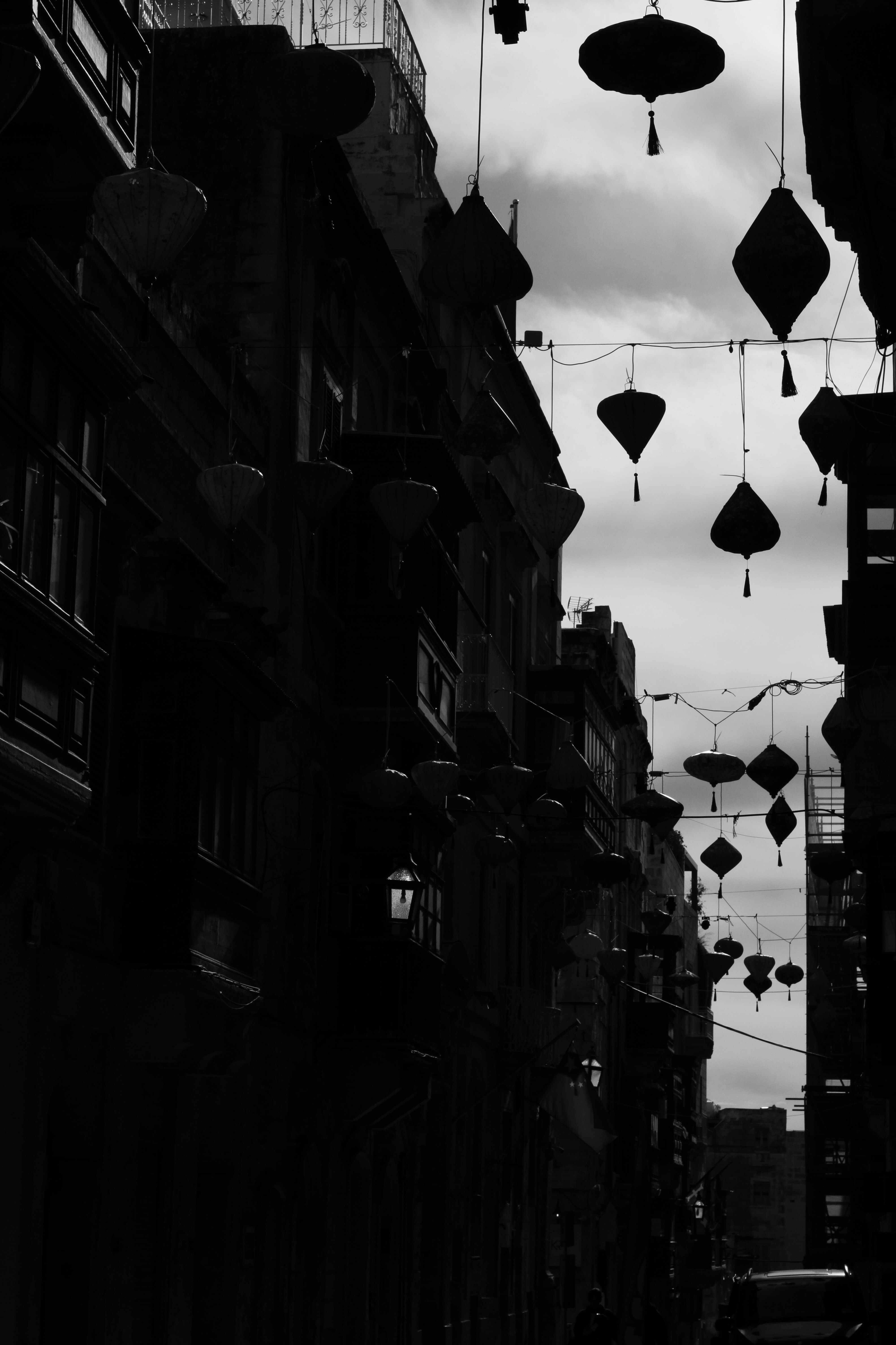 Laternen hängen zwischen den Gebäuden unter einem bewölkten Himmel.