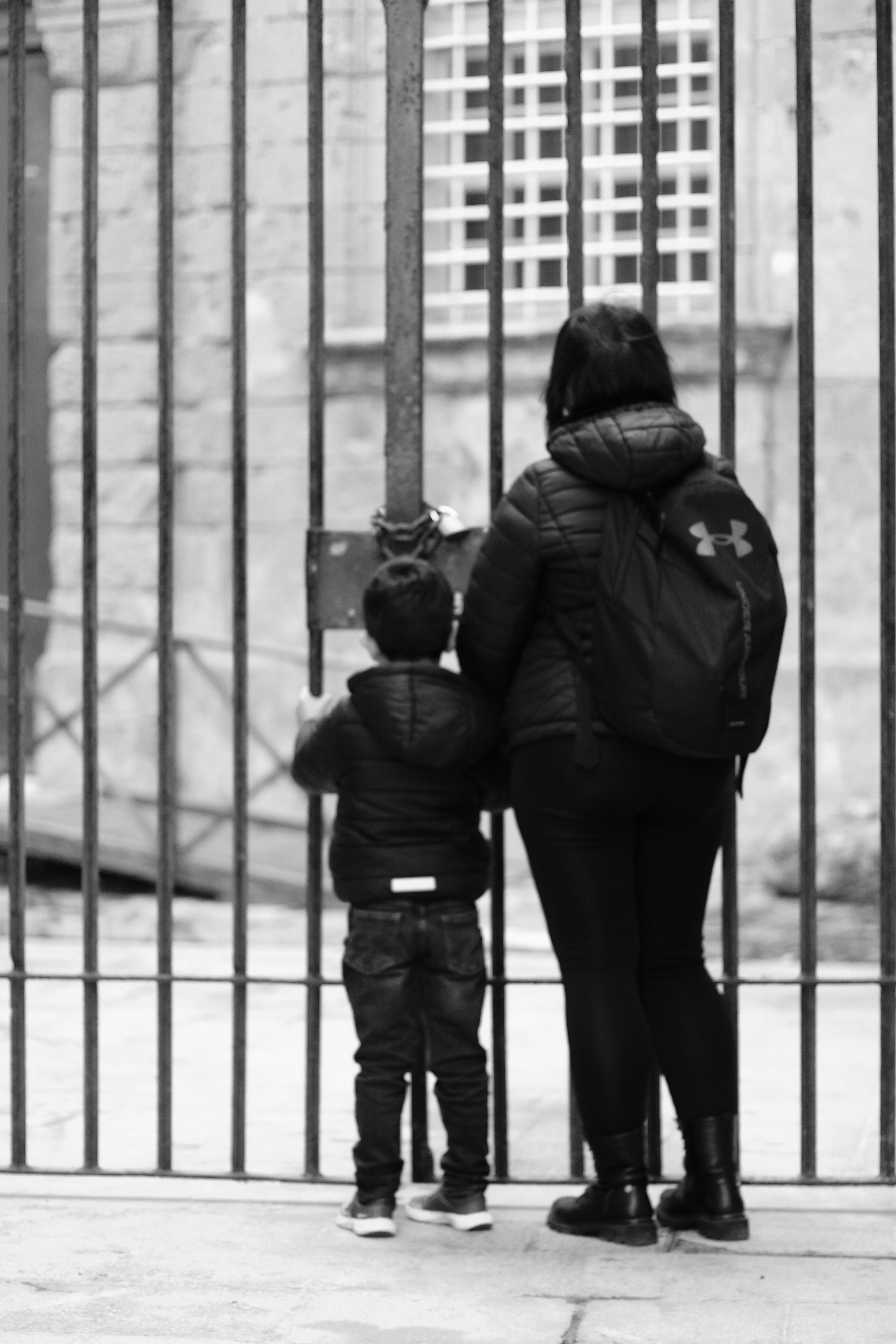 Mutter und Kind stehen an einem verschlossenen Tor