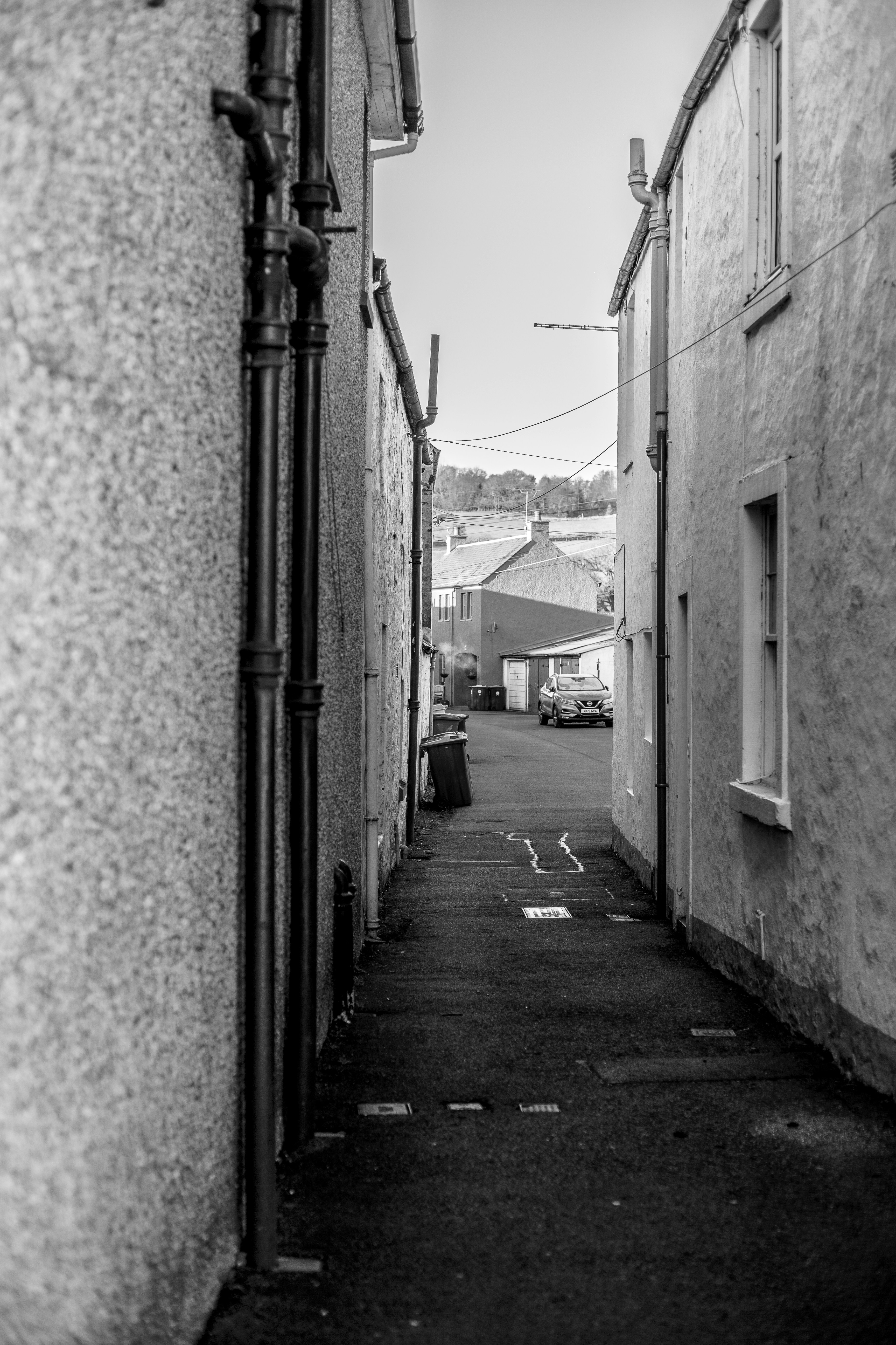 Schmale Gasse zwischen den Gebäuden mit einem Auto am Ende.