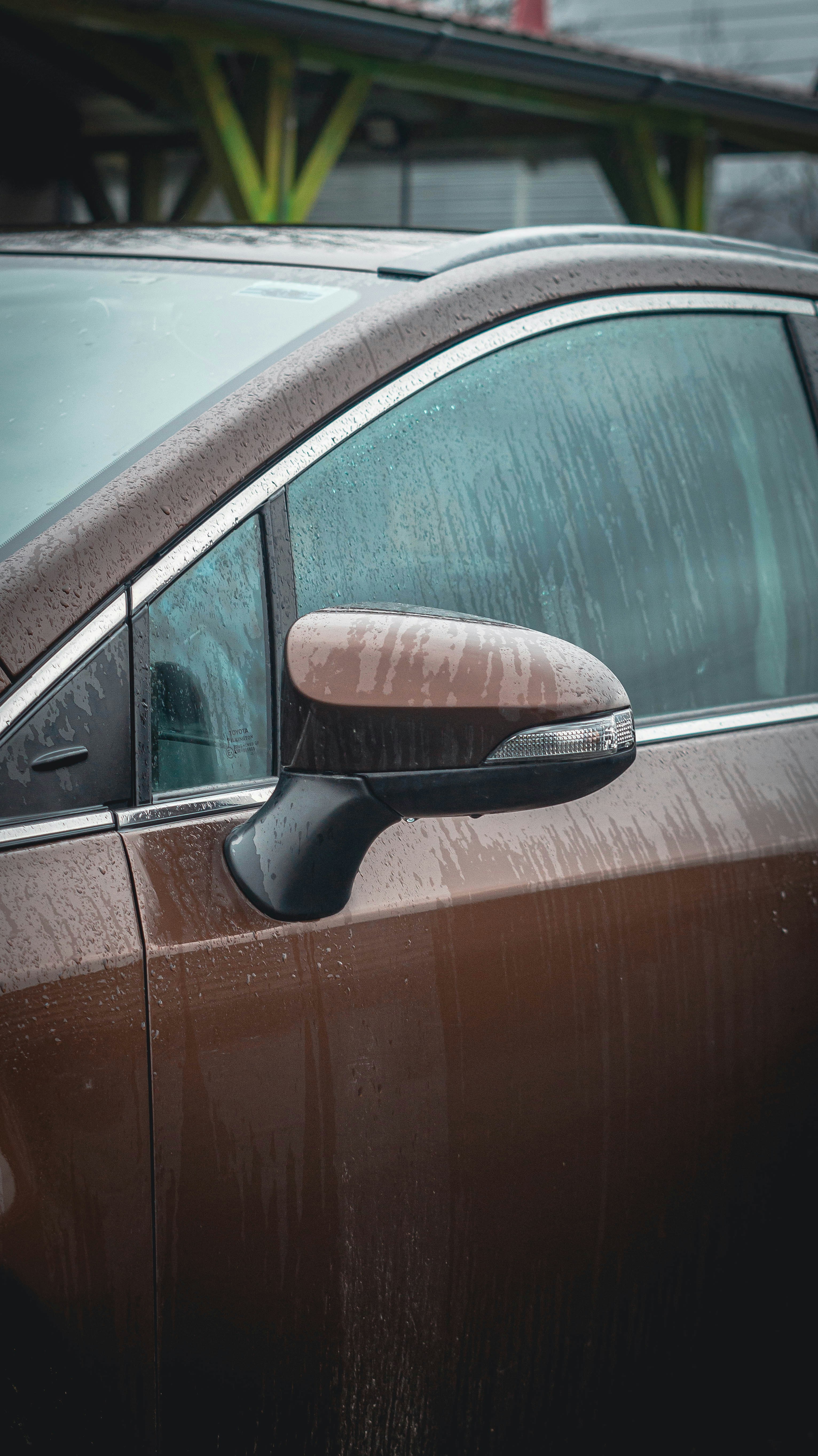 Brown car door covered in water droplets