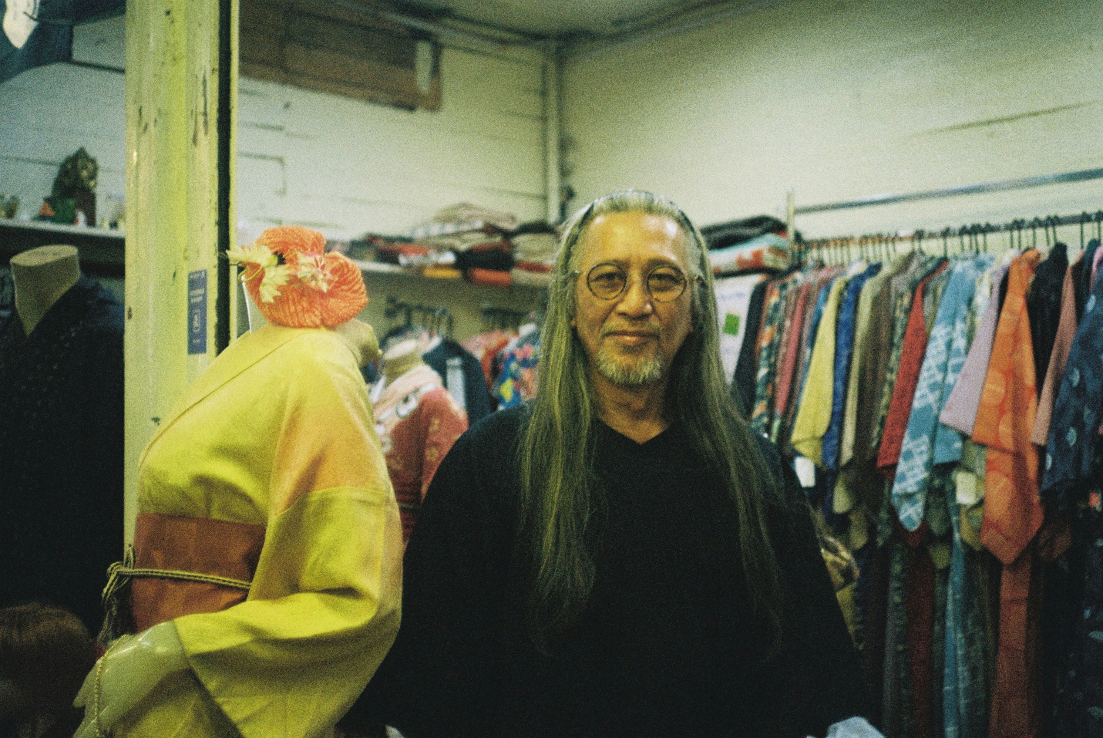 Man with long hair and glasses in a clothing store.