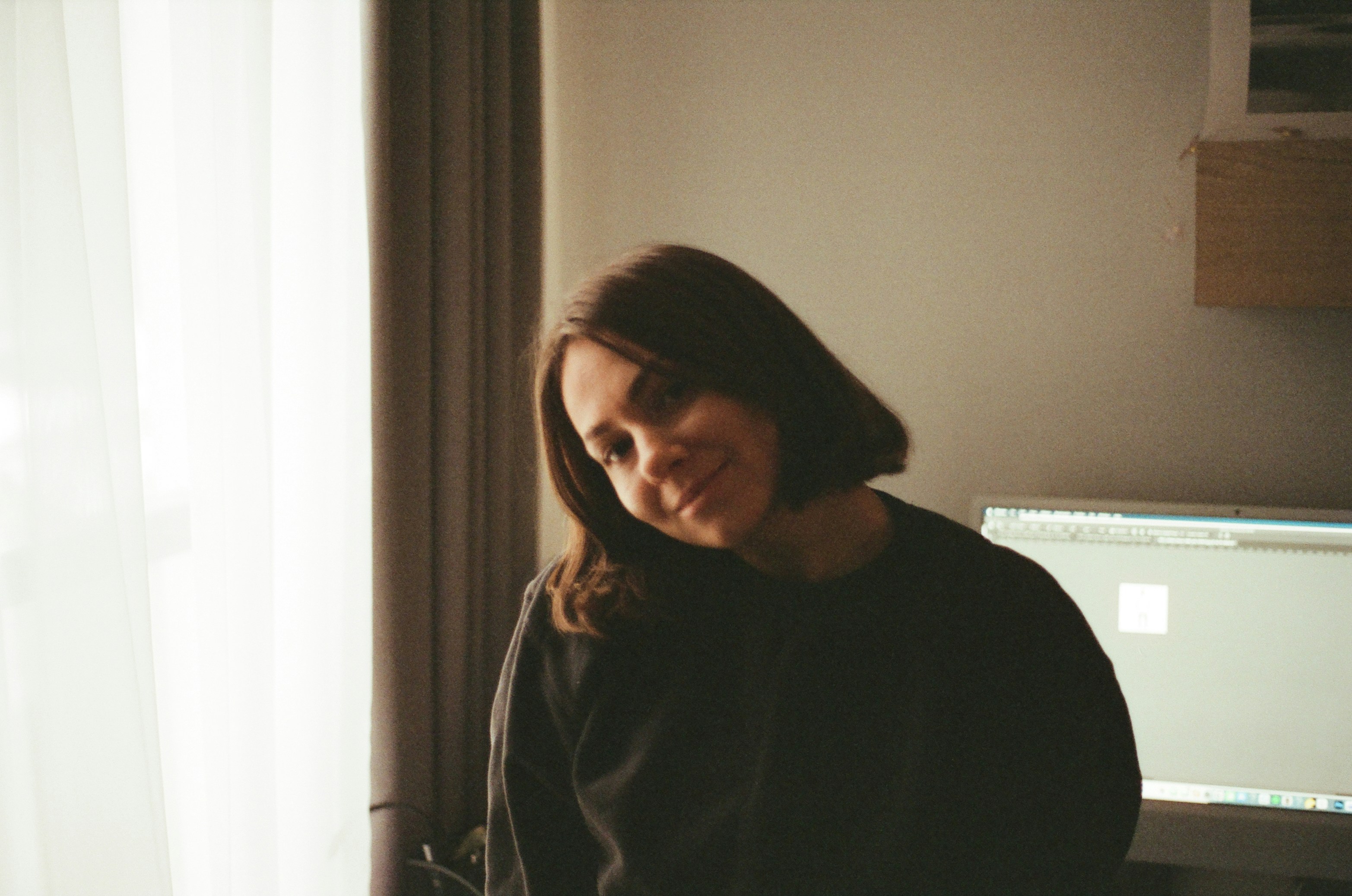 Young woman with short brown hair smiles gently tilts head