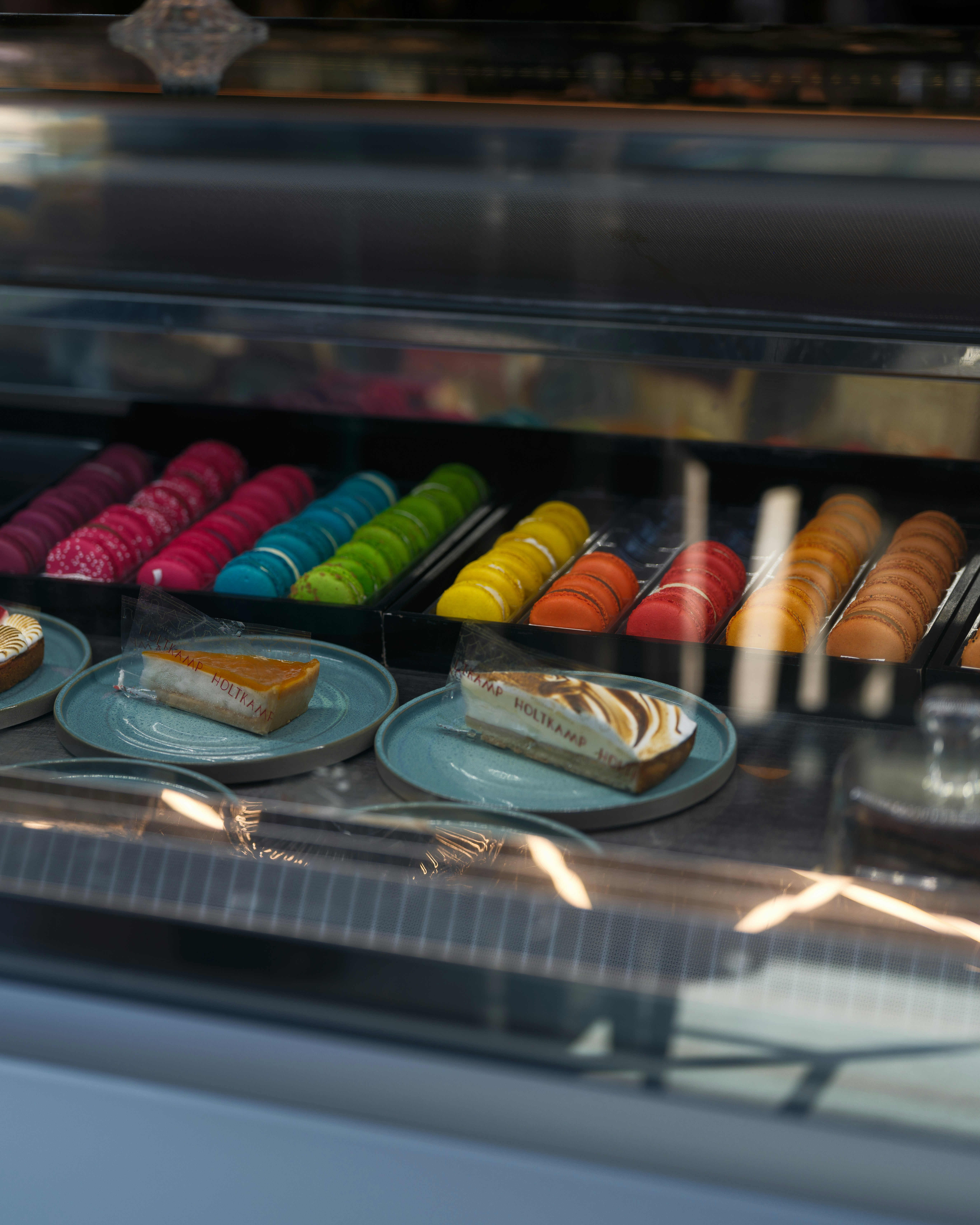 Colorful macarons and slices of cake in a display case