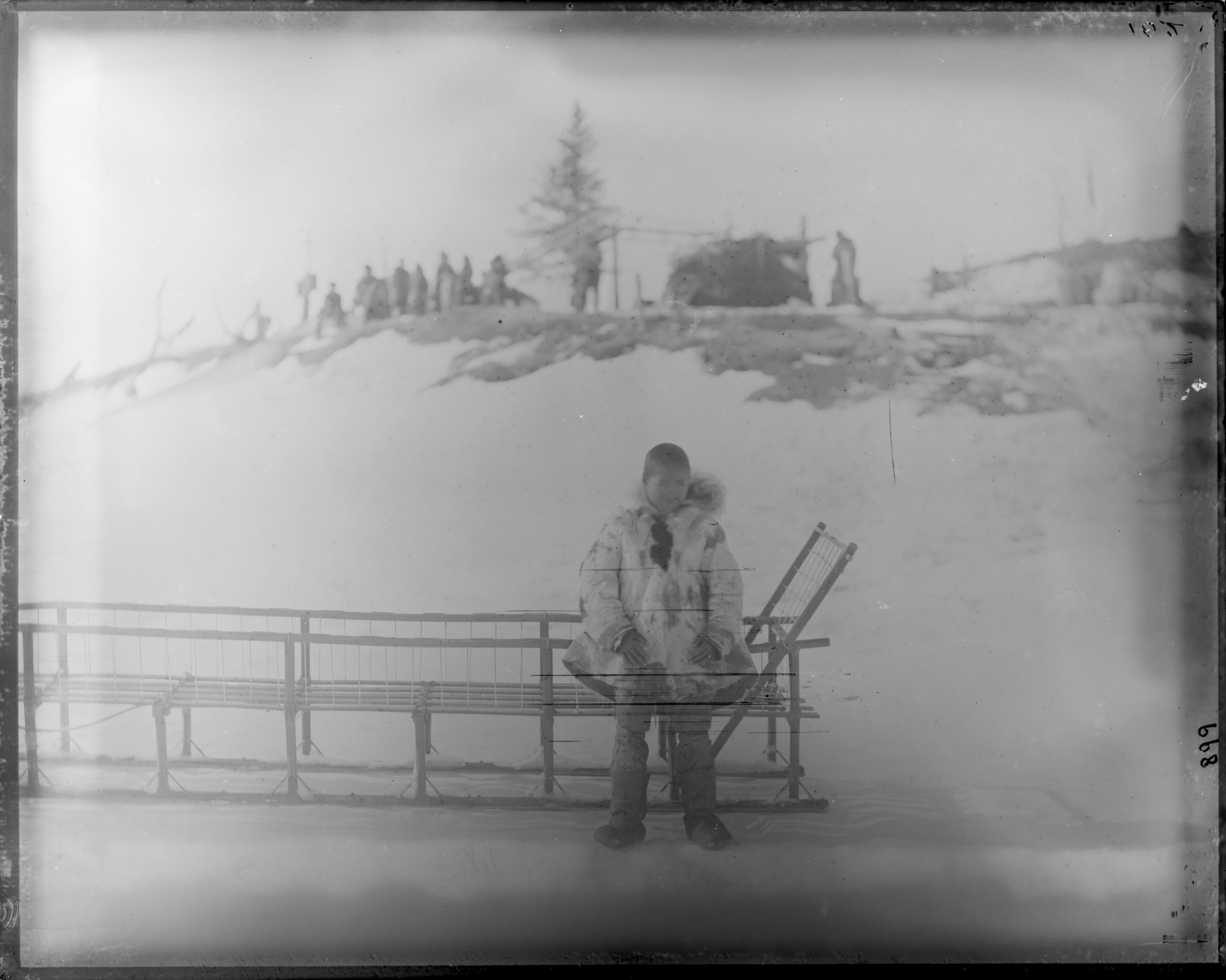 Hombre con parka y trineo en un paisaje nevado