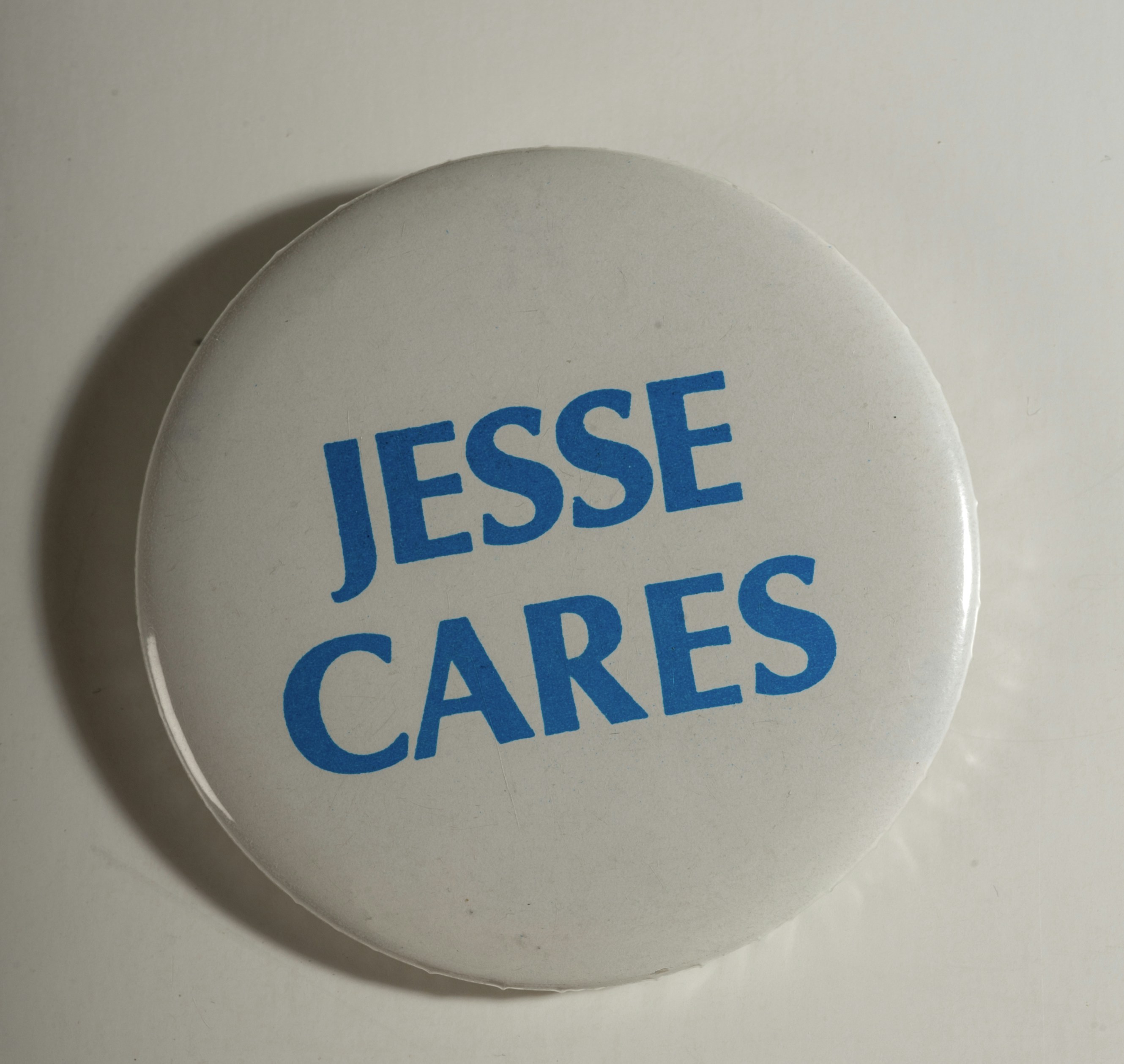 Weißer Knopf mit blauem Text "jesse cares"