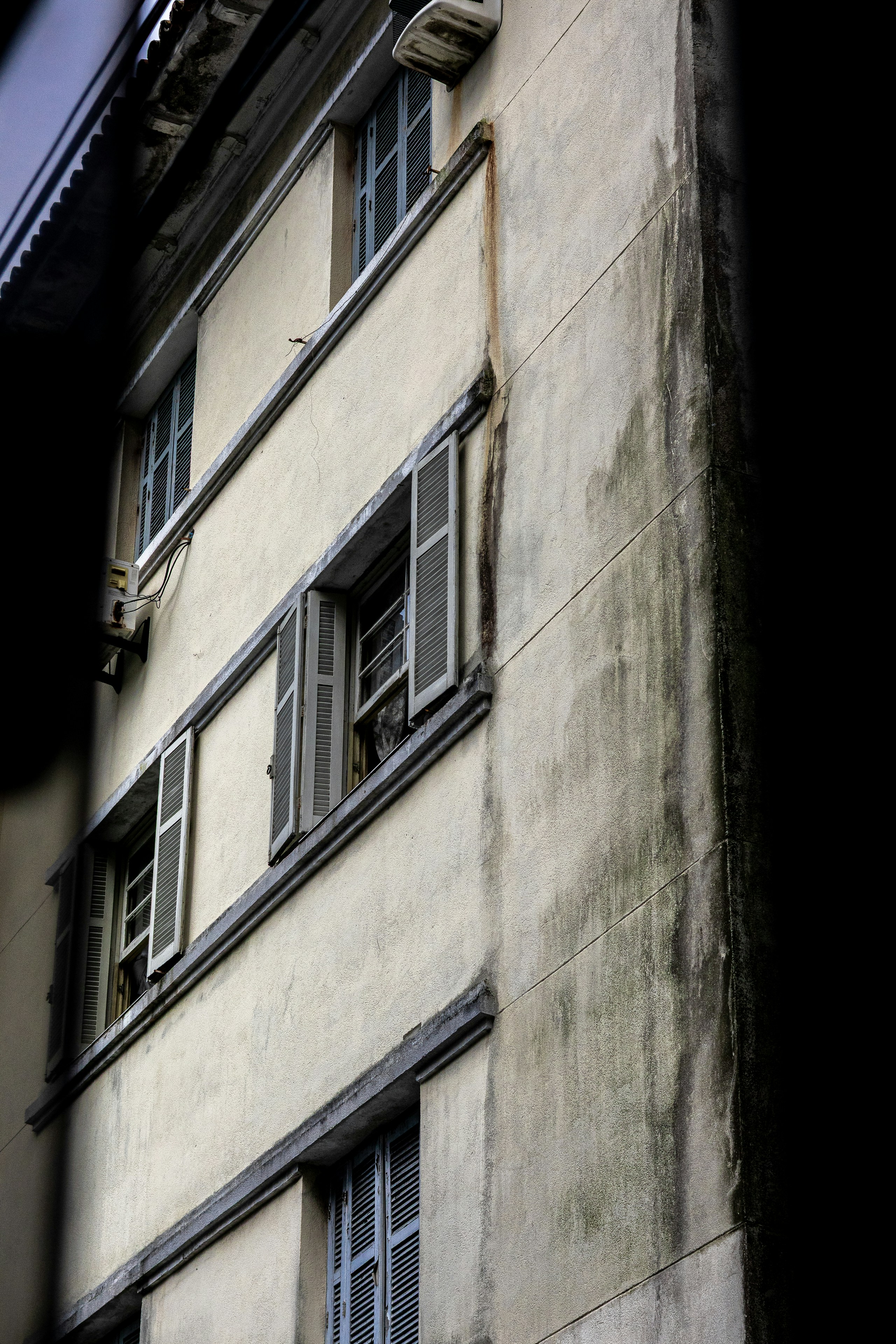 A close-up of a weathered building facade with multiple windows.