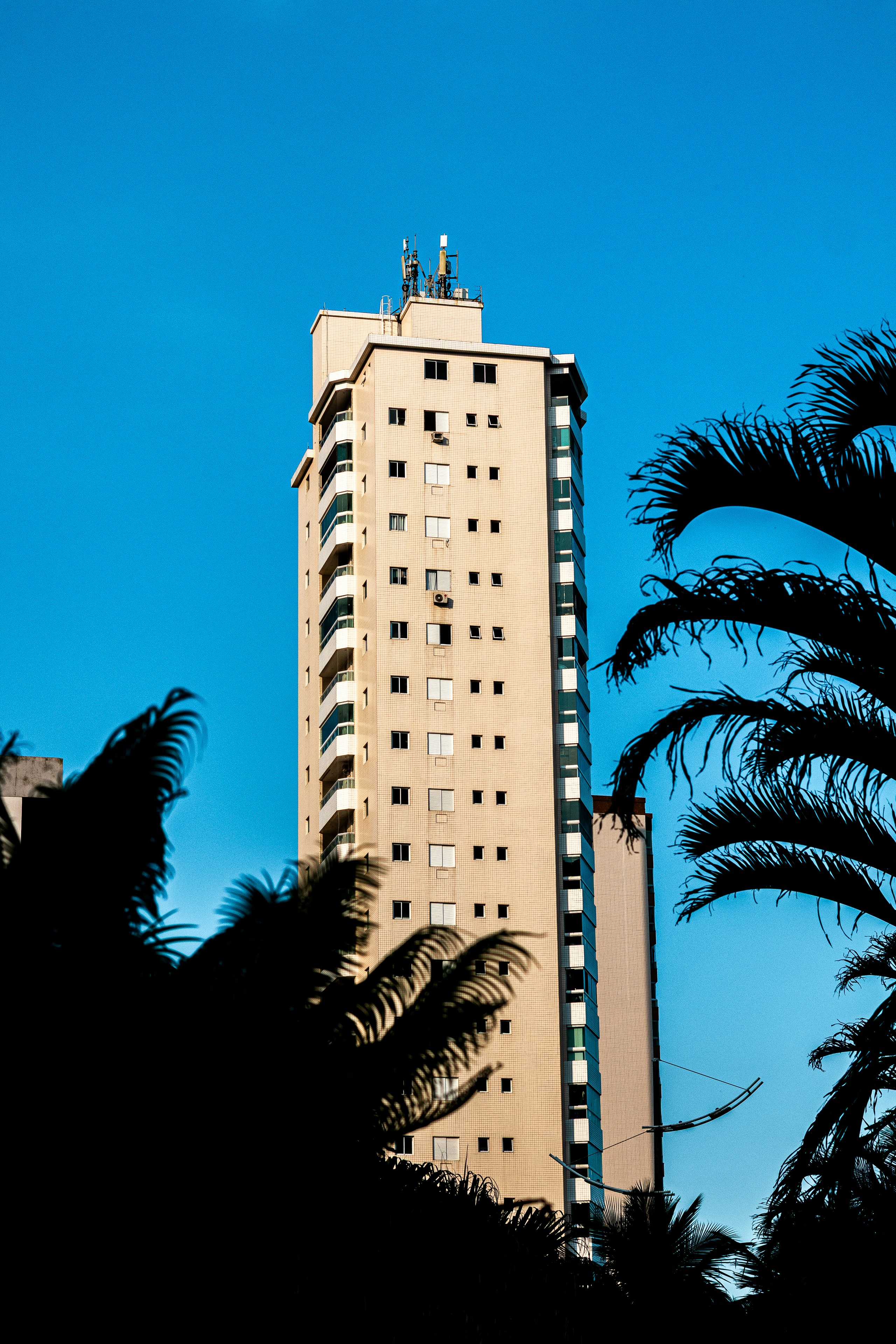 Tall apartment building against a clear blue sky.