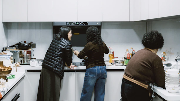 Three people in a modern kitchen preparing food.