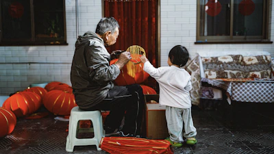 An older man and a child prepare red lanterns.