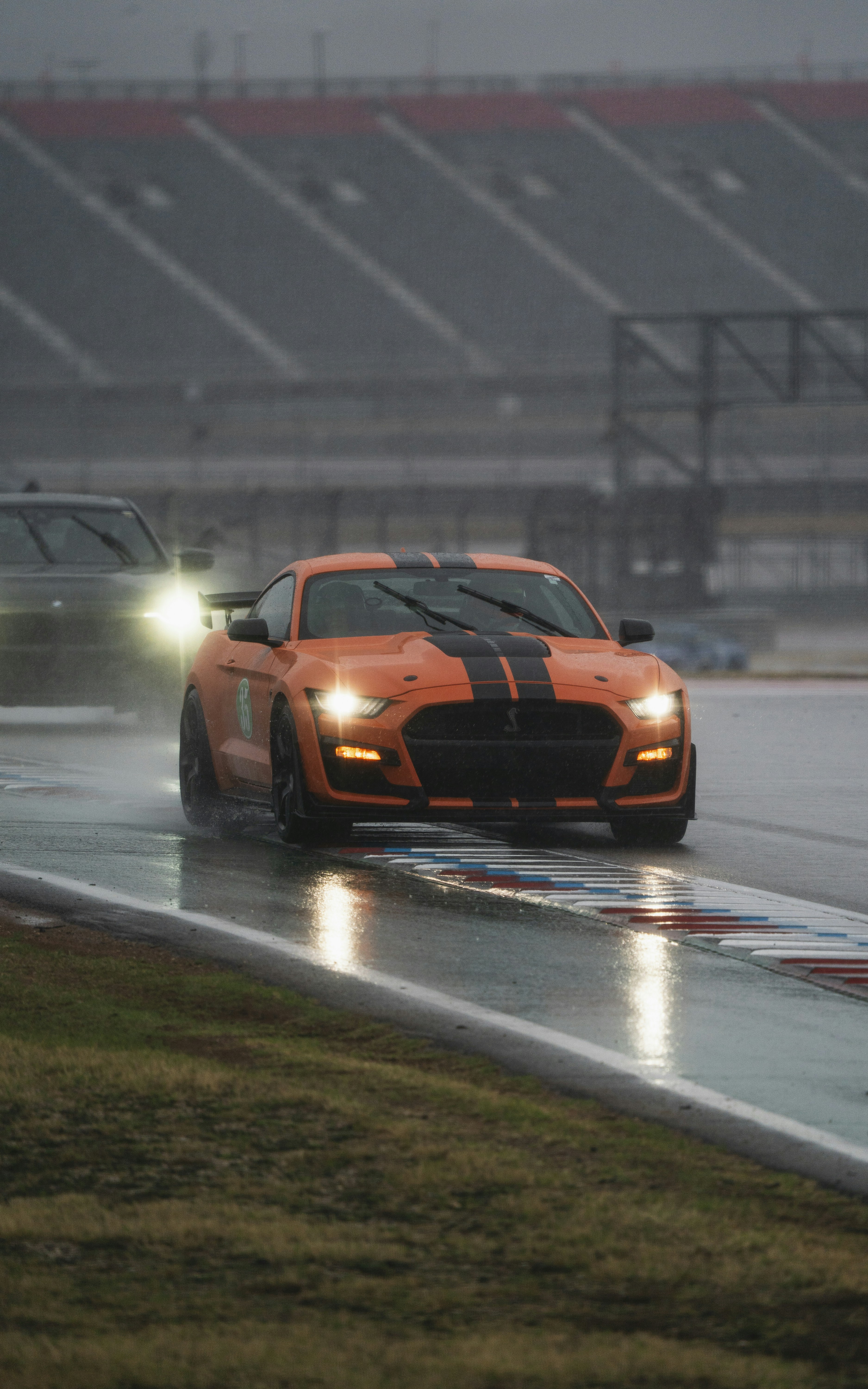 Orange sports car racing on a wet track.