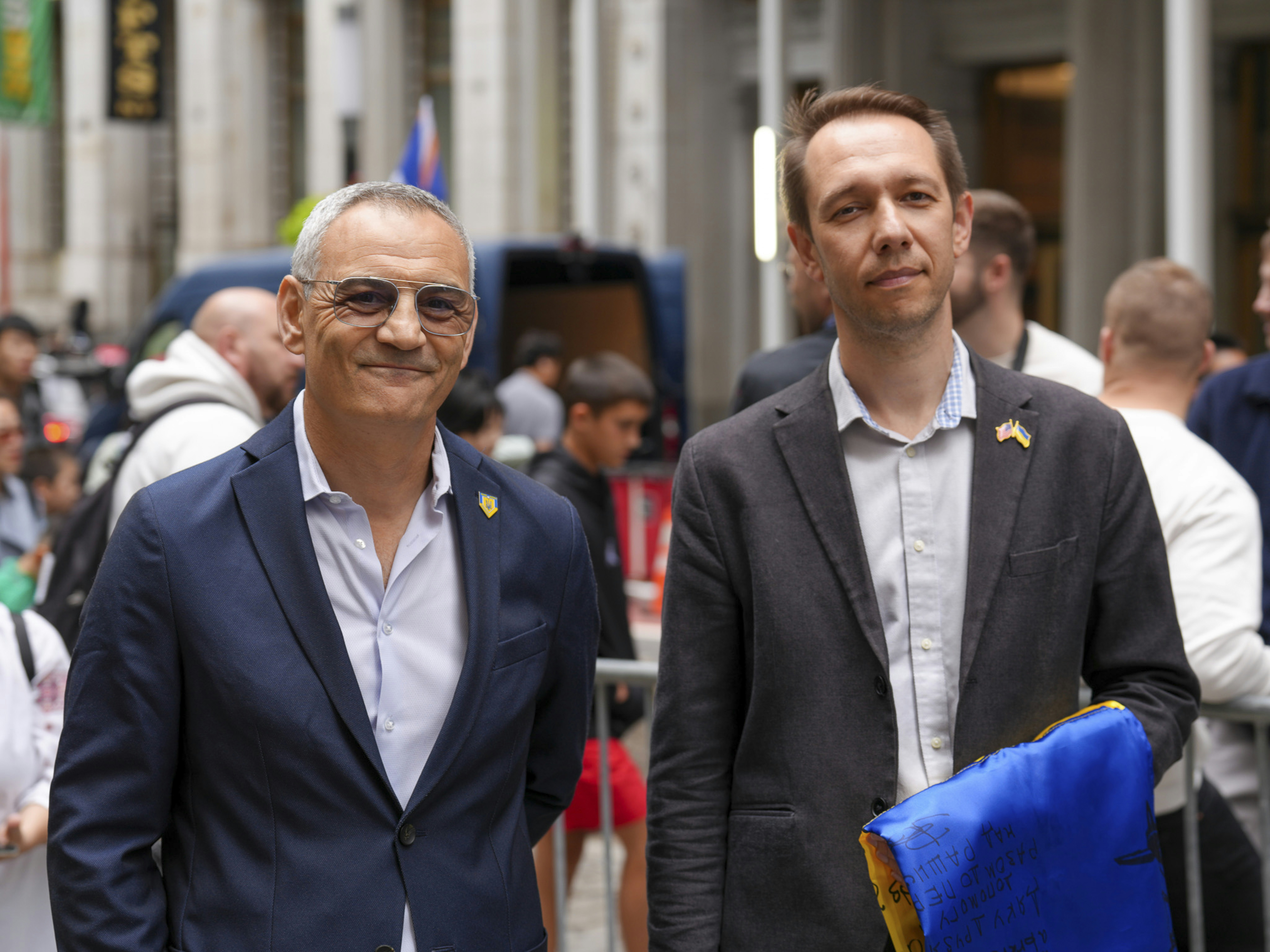 Two men in suits smiling at an outdoor event