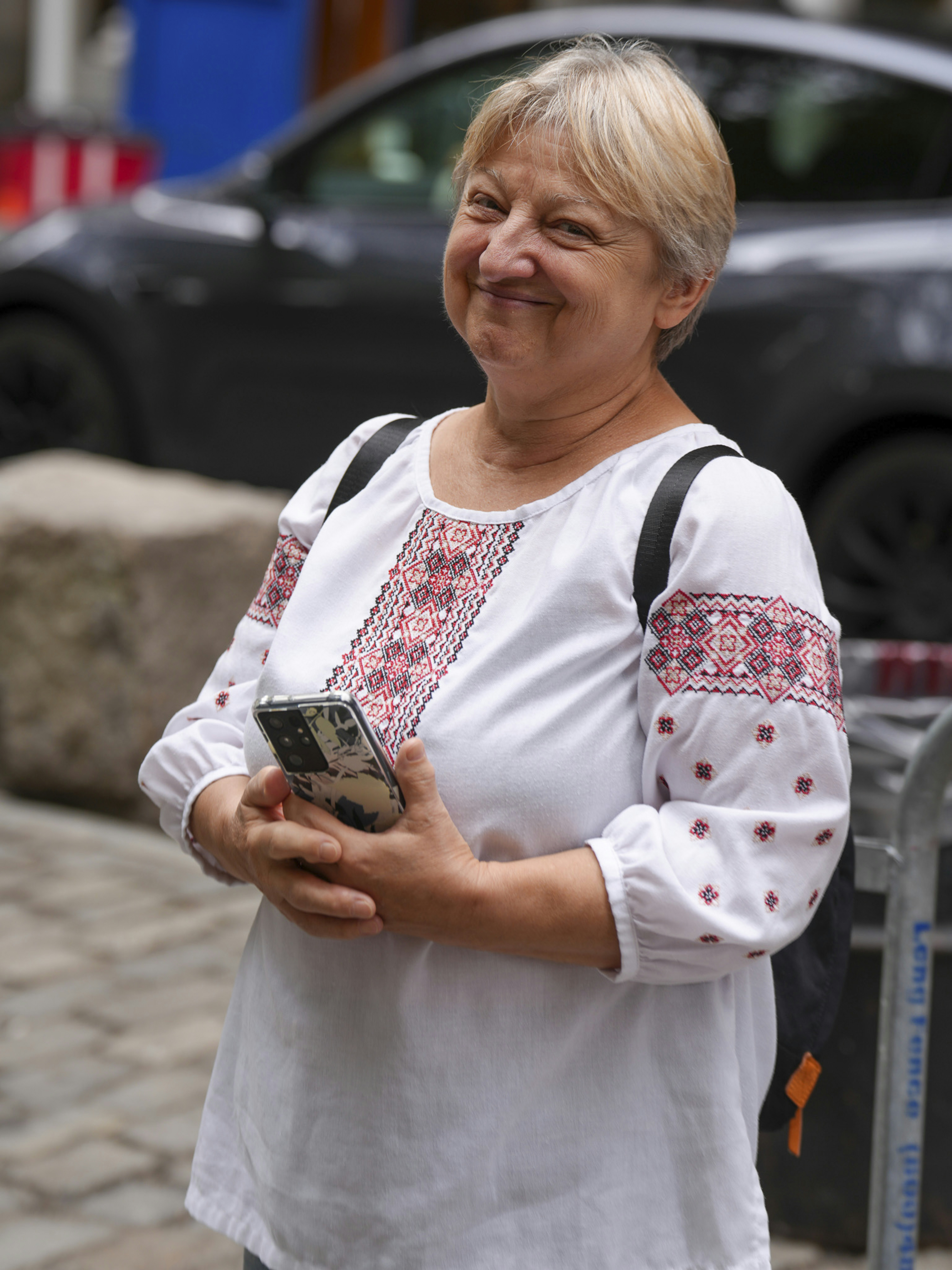 Woman in embroidered shirt holding a smartphone