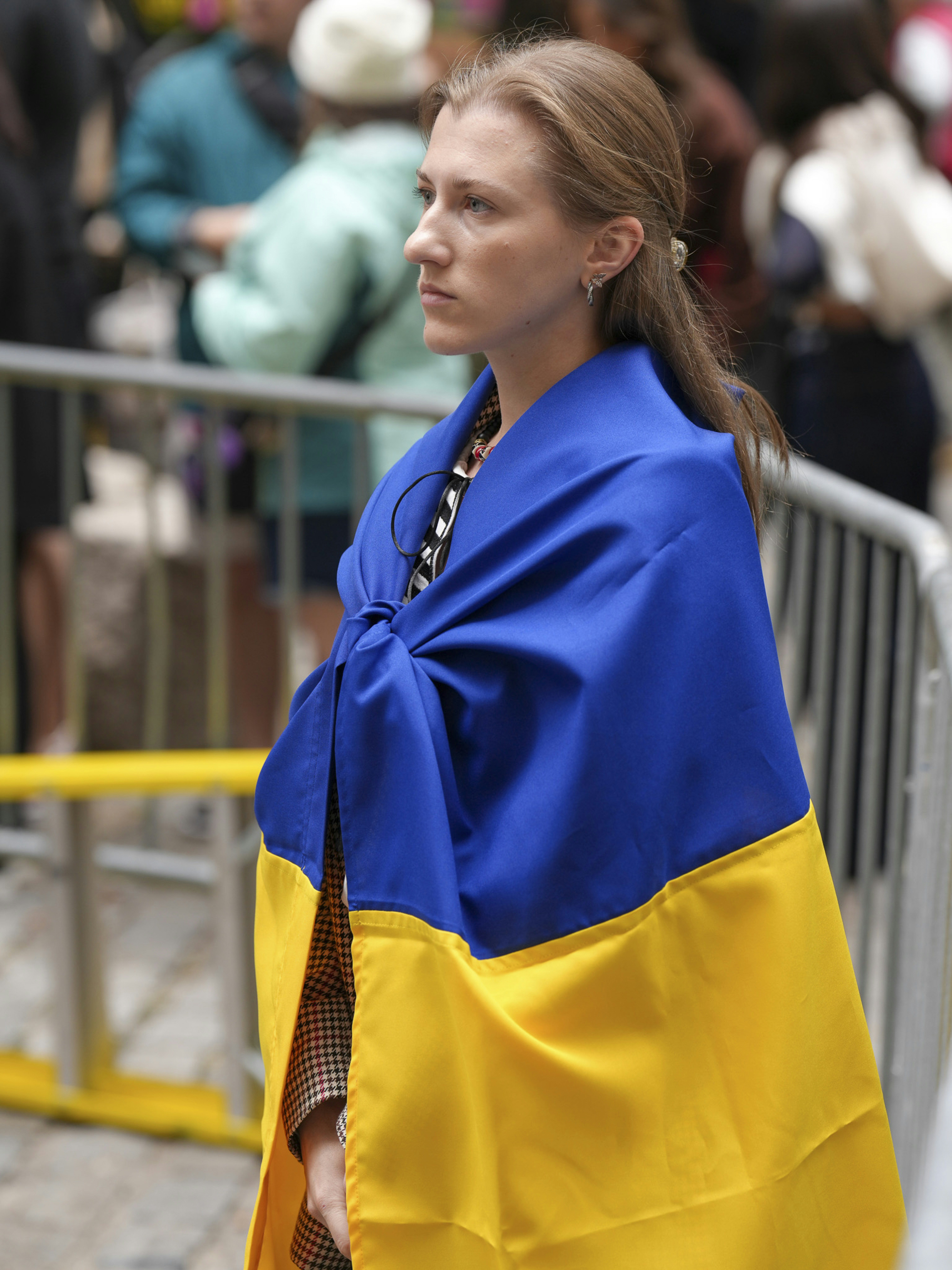 Woman draped in ukrainian flag looks thoughtfully aside