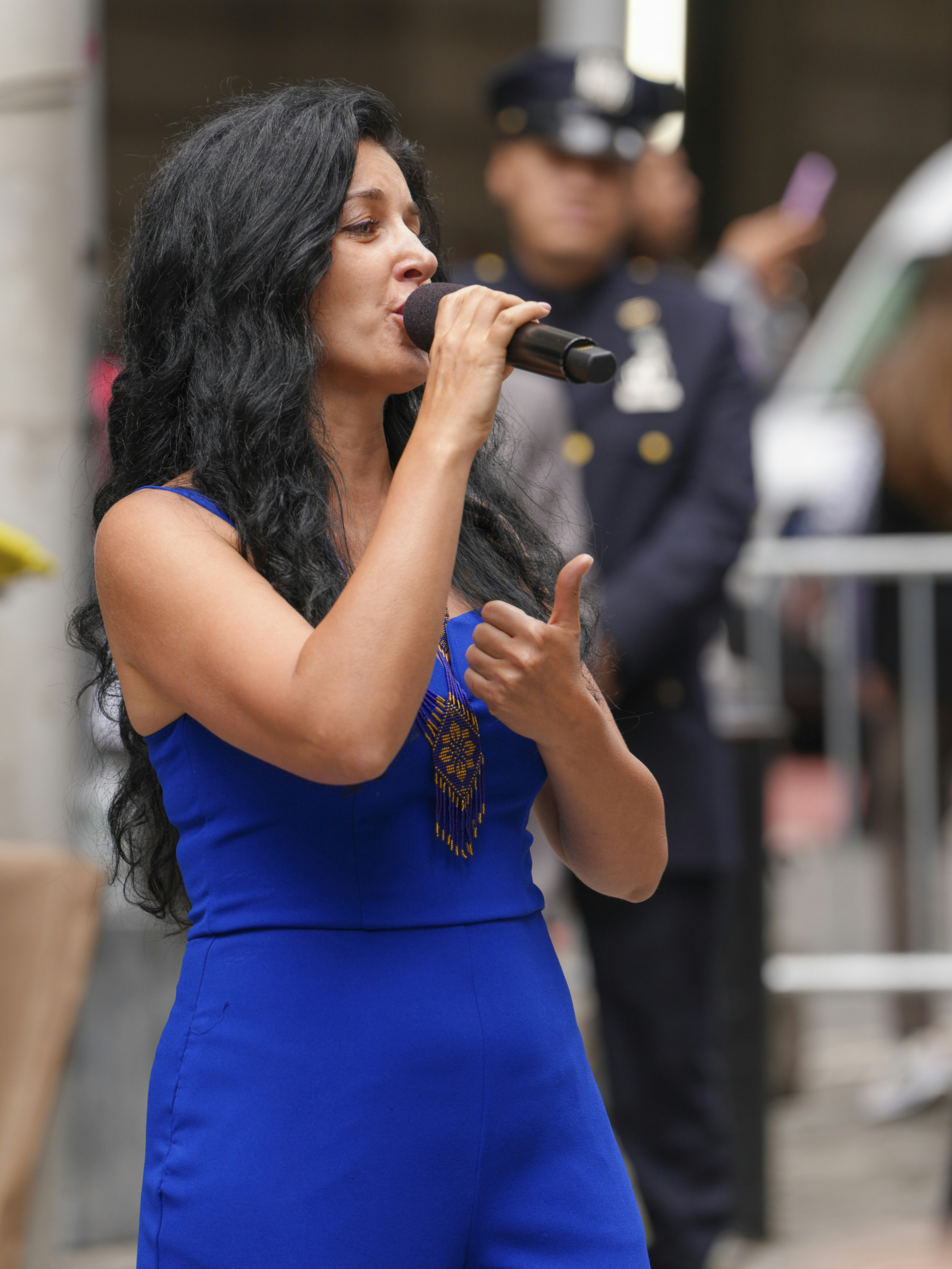 A woman in a blue dress sings into a microphone.