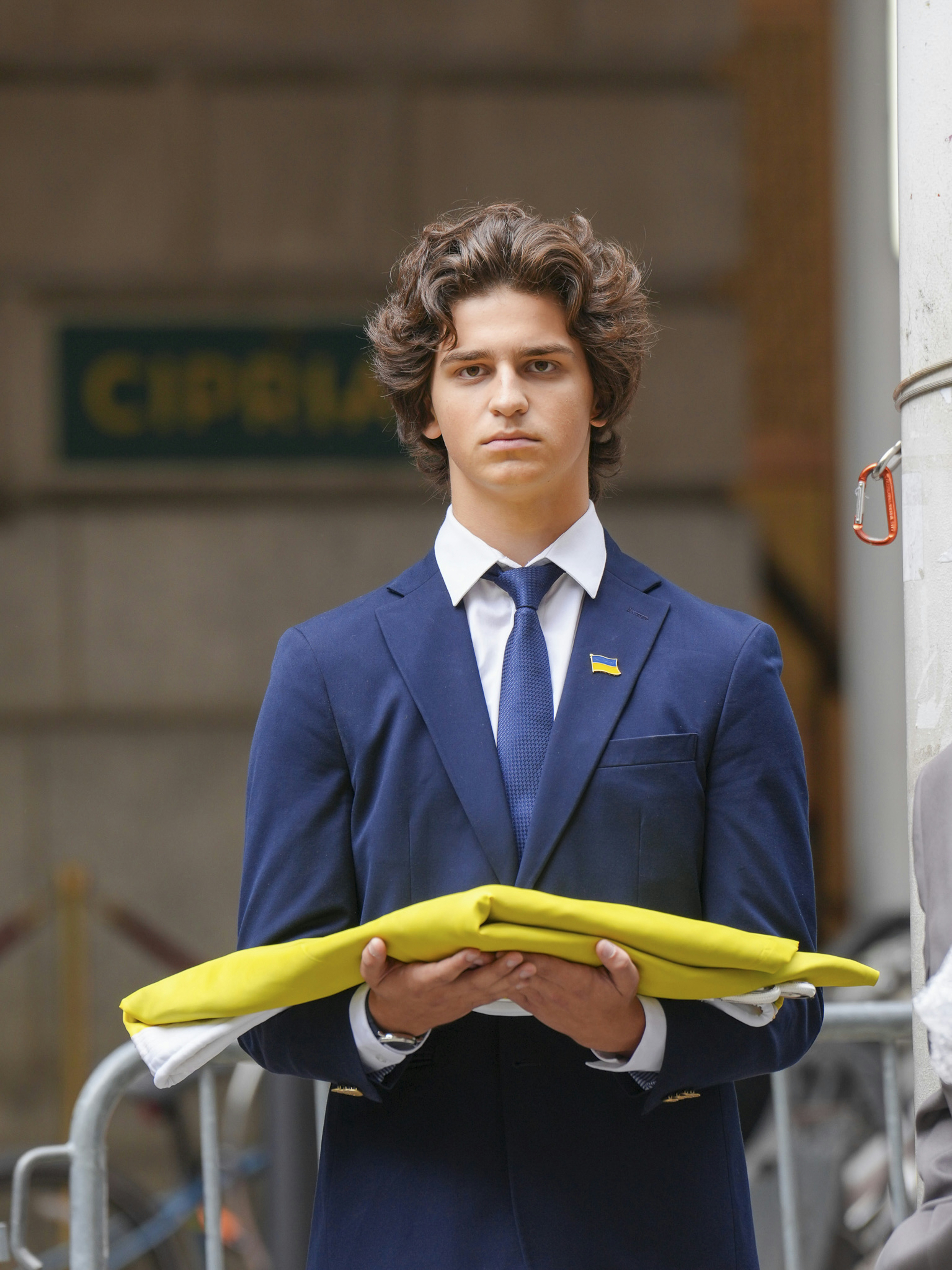 Young man in suit holding yellow and blue flag