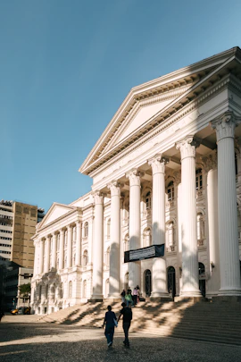 People walk towards a grand neoclassical building.