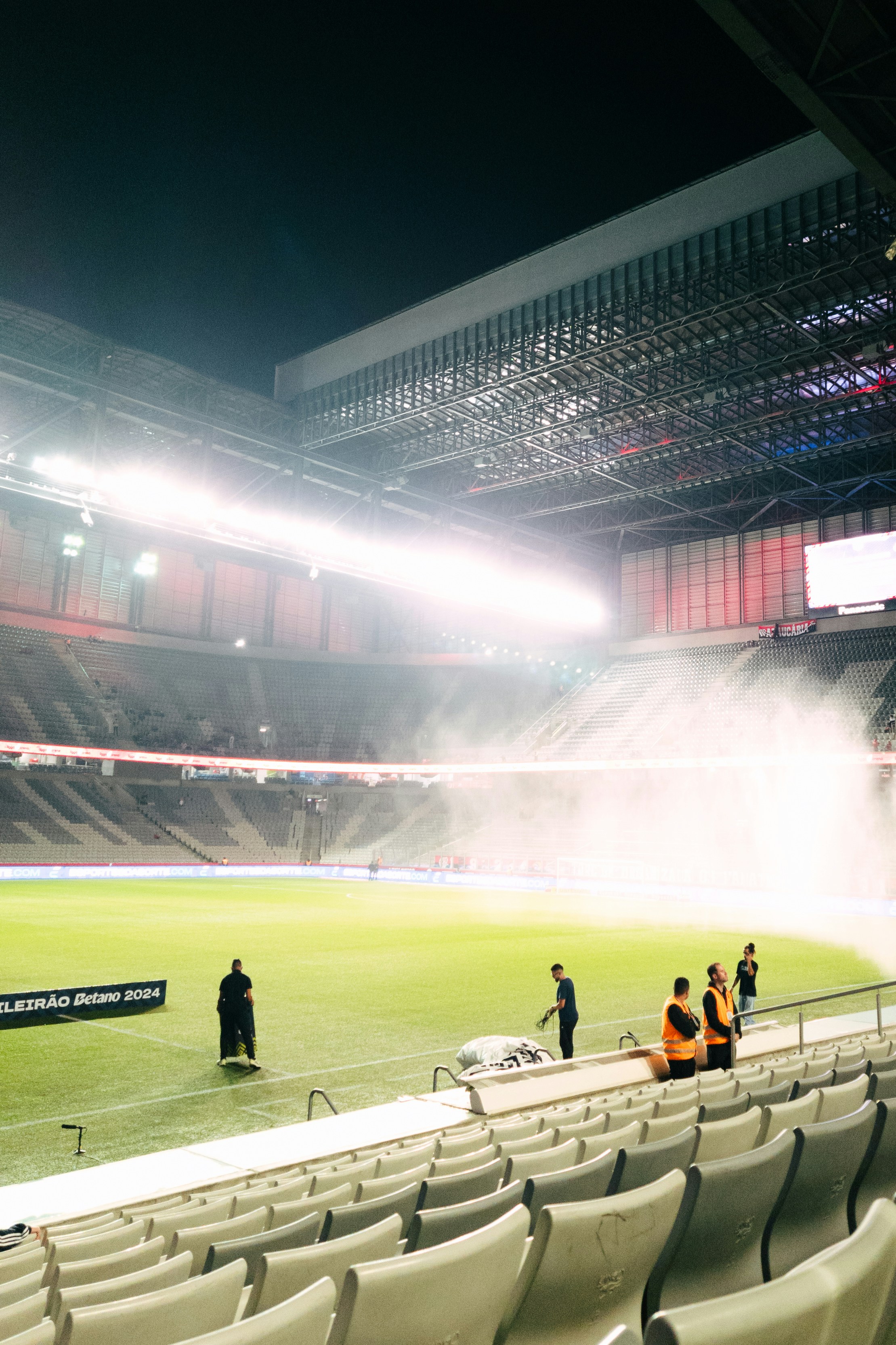 Trabajadores del estadio regando el campo por la noche