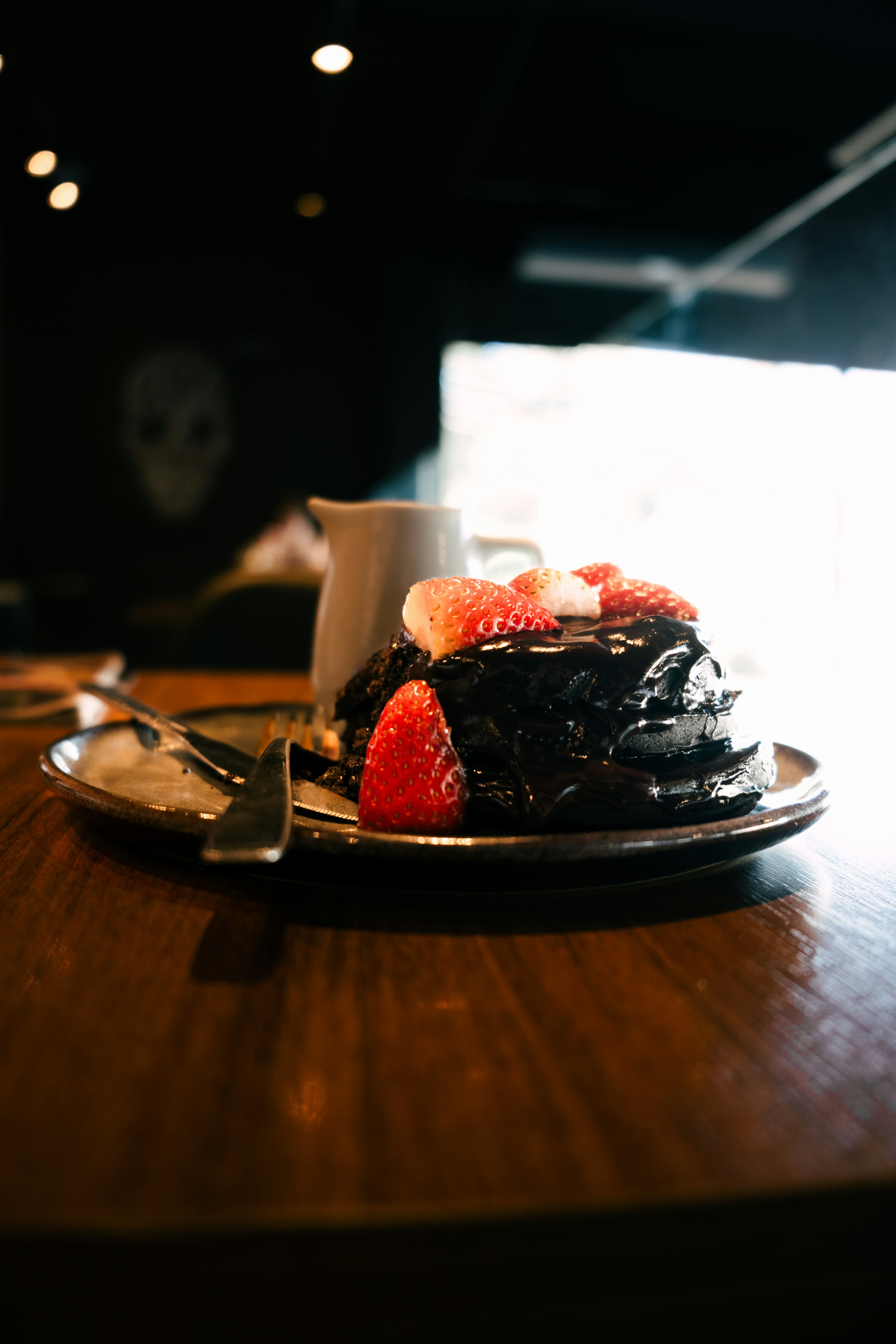 Dark chocolate pancakes with fresh strawberries on top.
