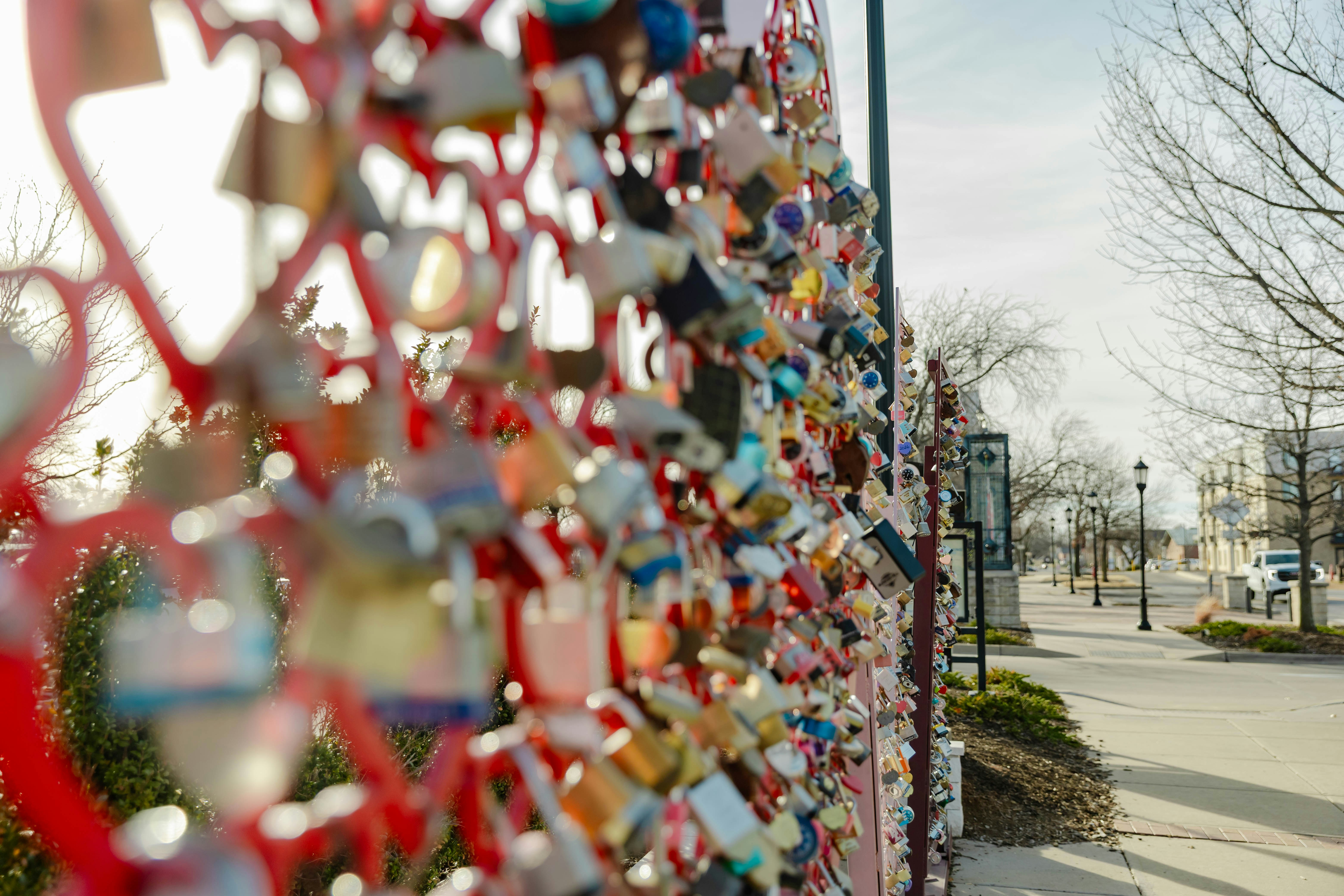 Many colorful love locks attached to a red fence.