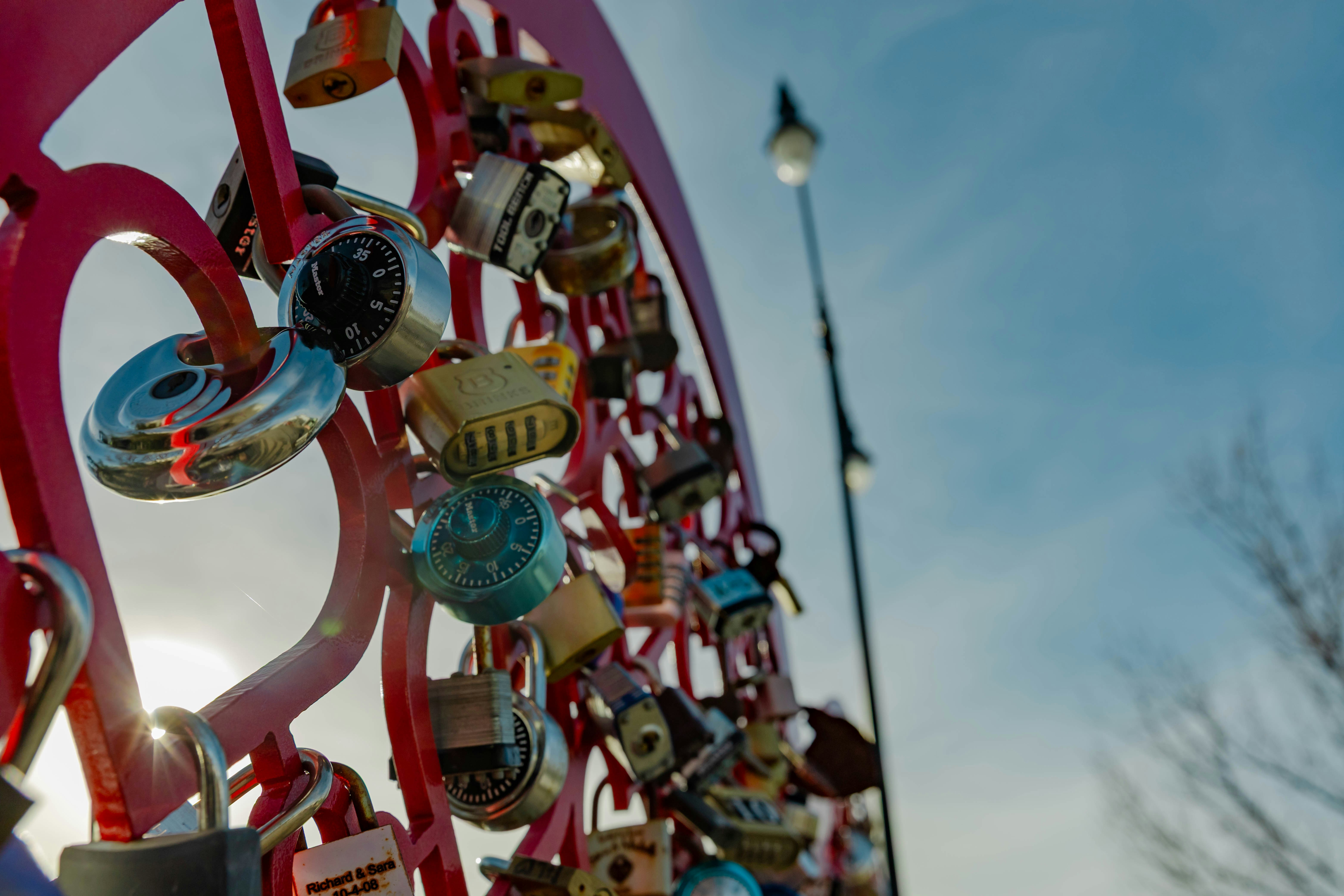 Many padlocks attached to a pink metal structure.