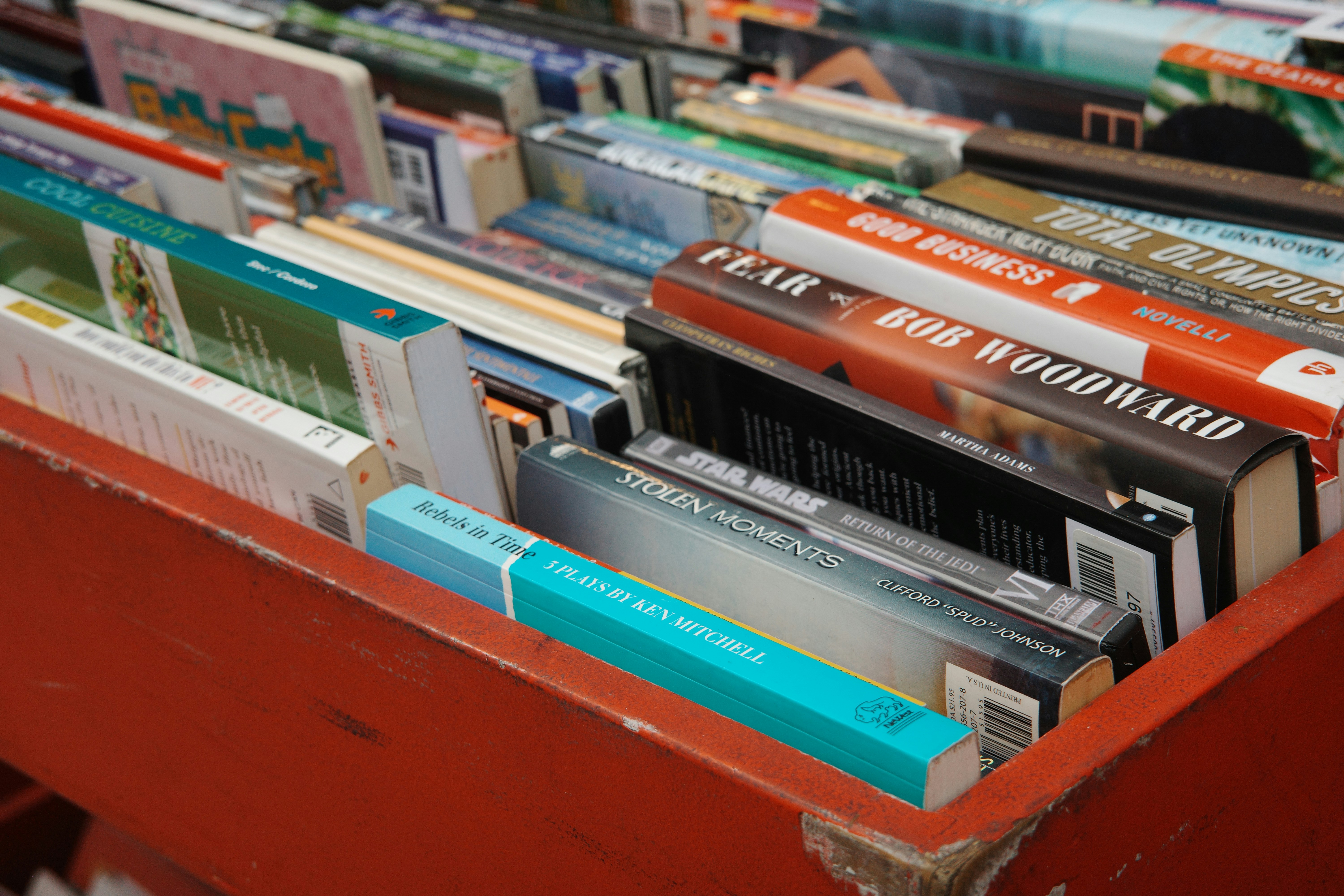 Un contenedor rojo repleto de libros y novelas variados.