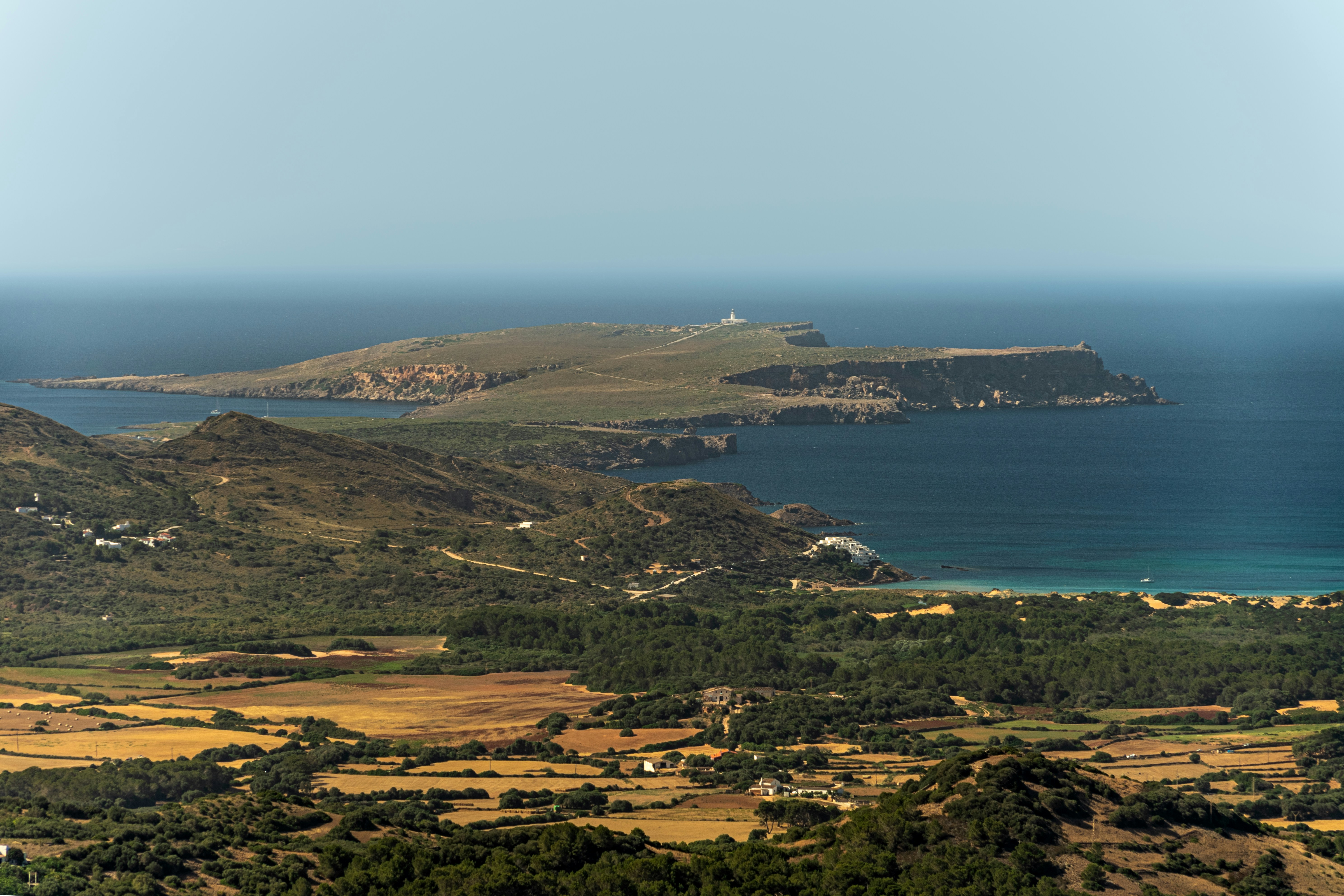 Coastal landscape with island and lighthouse in distance