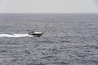 A motorboat speeds across the choppy grey ocean.