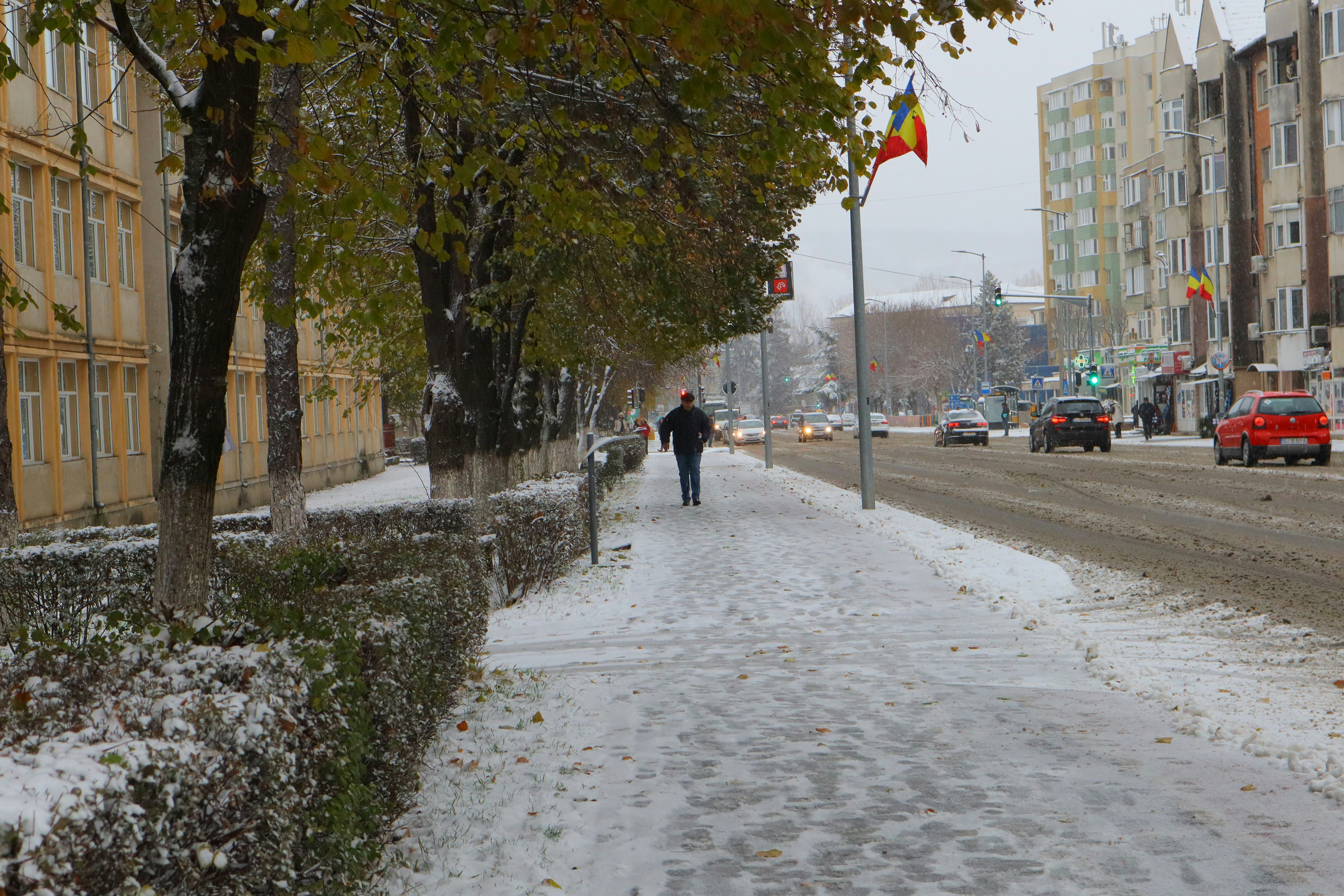 男が通り脇の雪に覆われた歩道を歩いている。