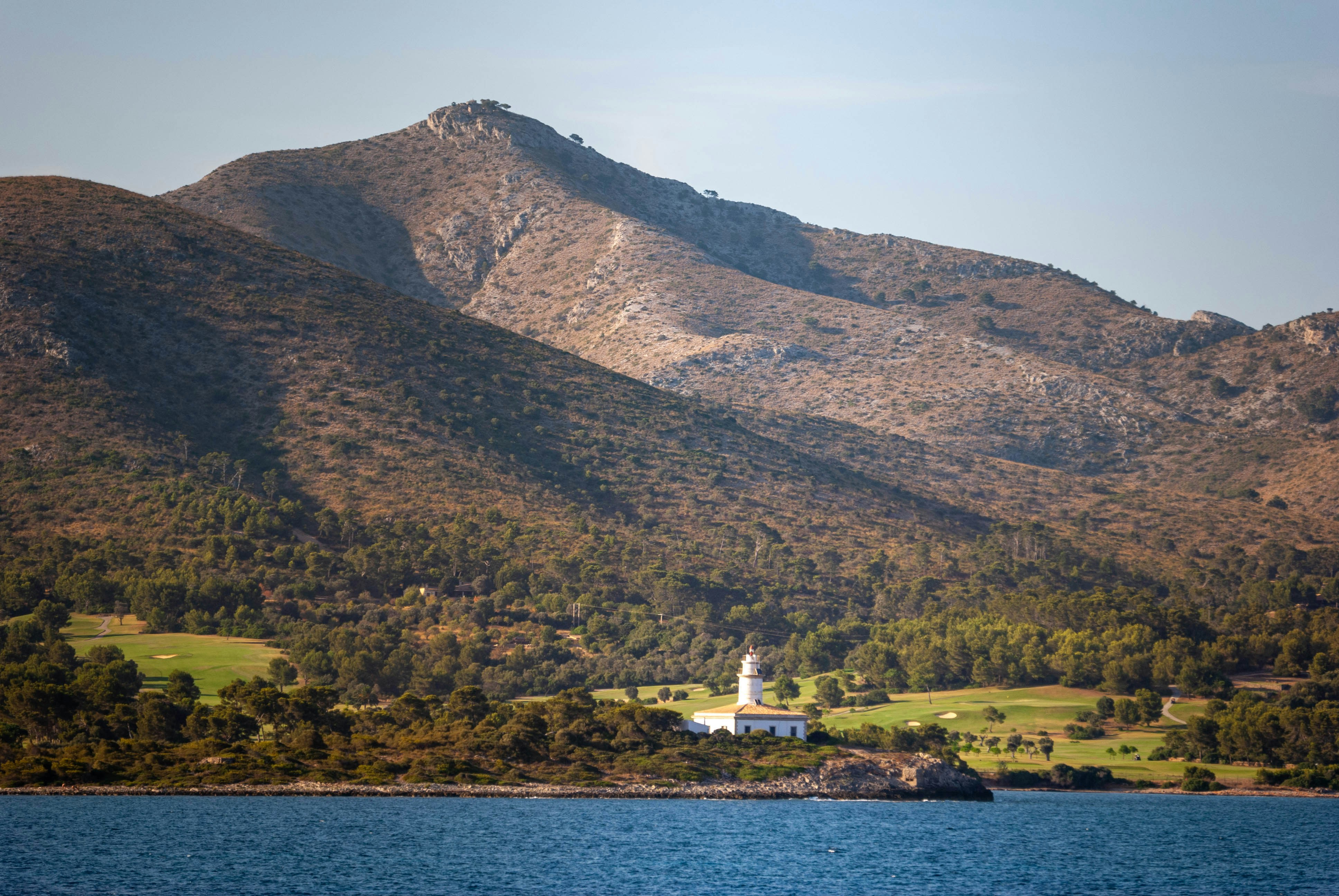 Lighthouse on a hill overlooking the blue ocean.