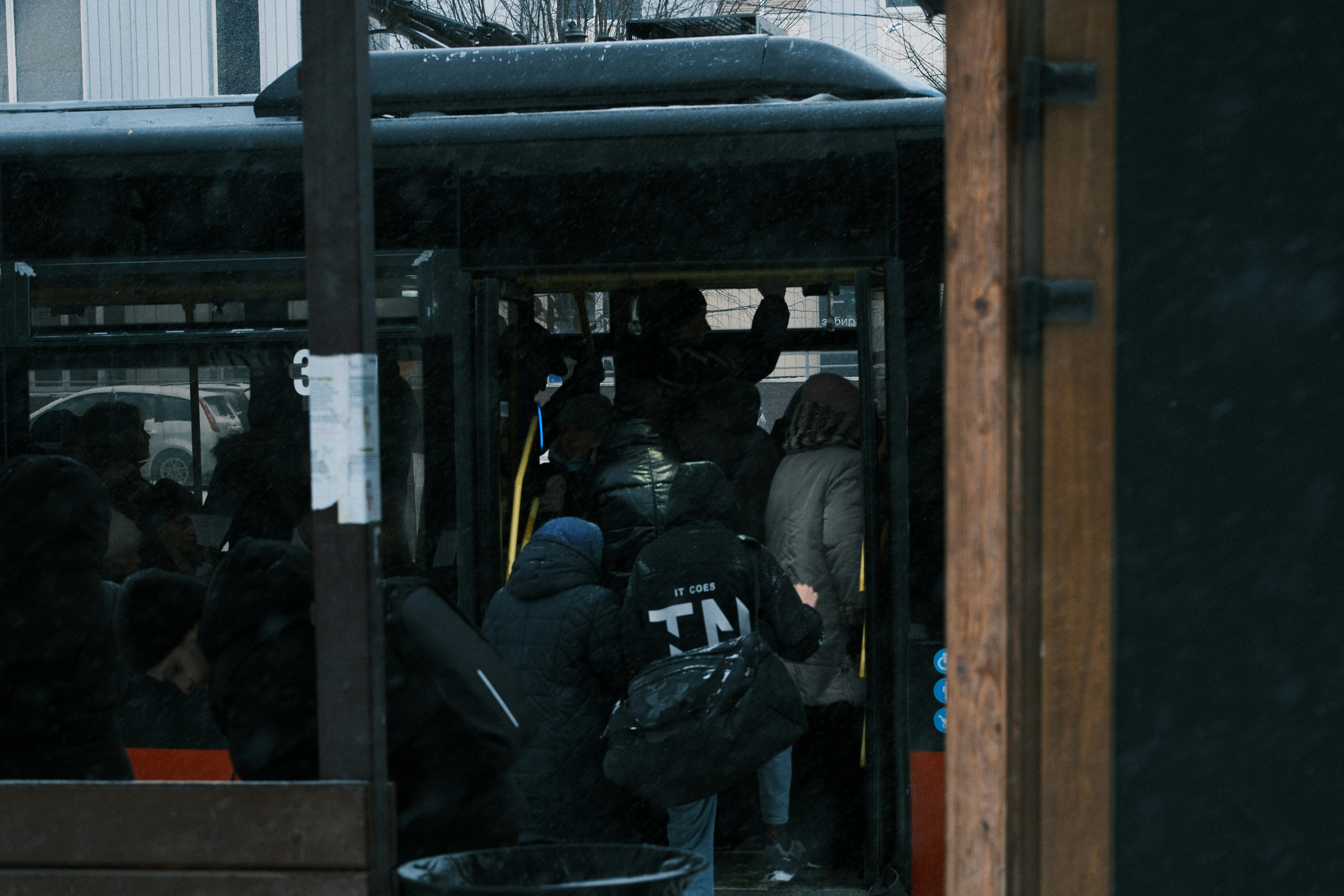 People boarding a crowded bus in the rain.