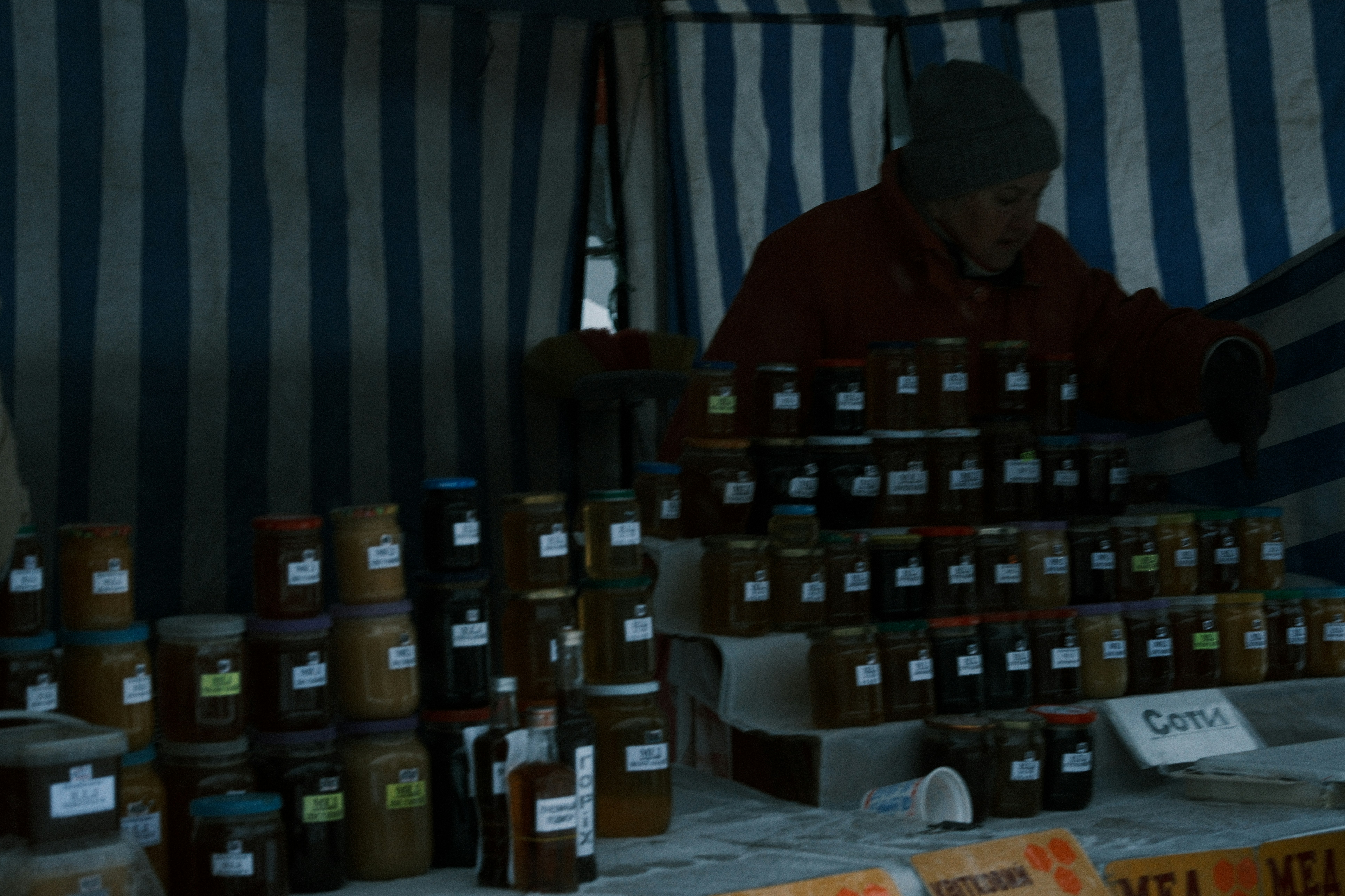 Vendor selling jars of honey at a market stall