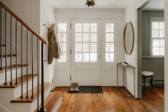 A cozy entryway with wooden stairs and a glass door.