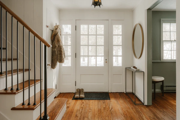 A cozy entryway with wooden stairs and a glass door.