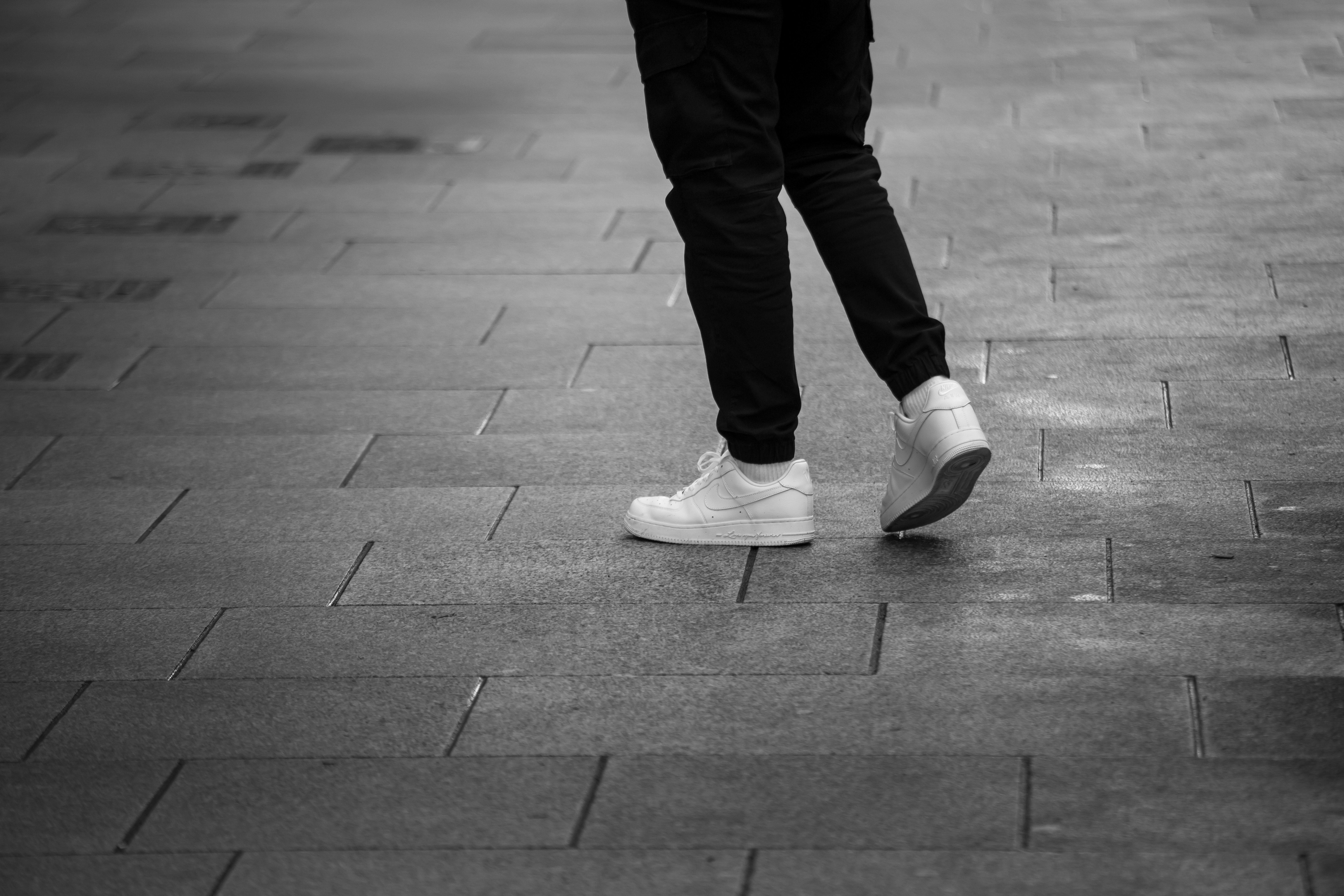A person walks on a tiled sidewalk.