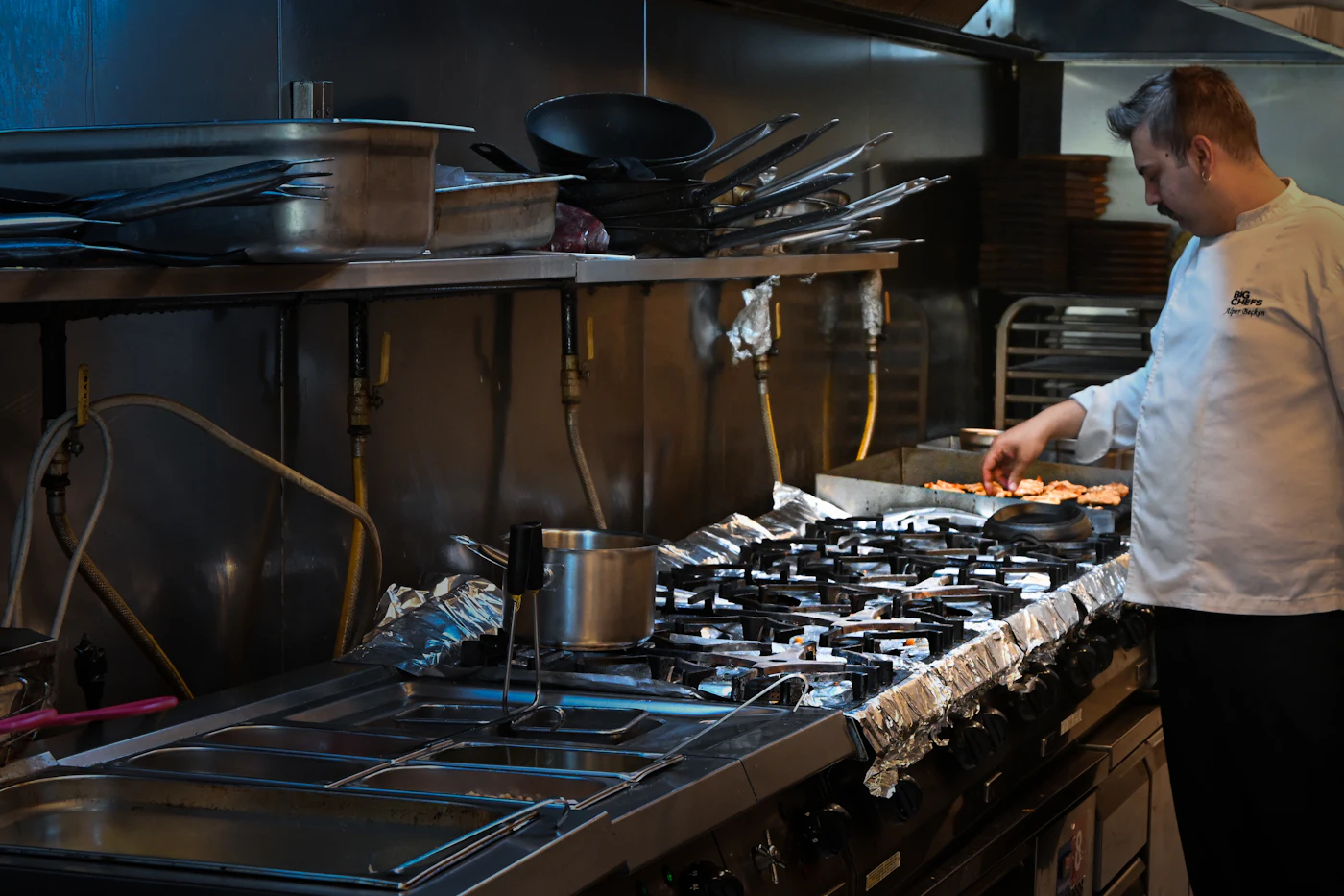 Commercial cook working at a large gas cooking range