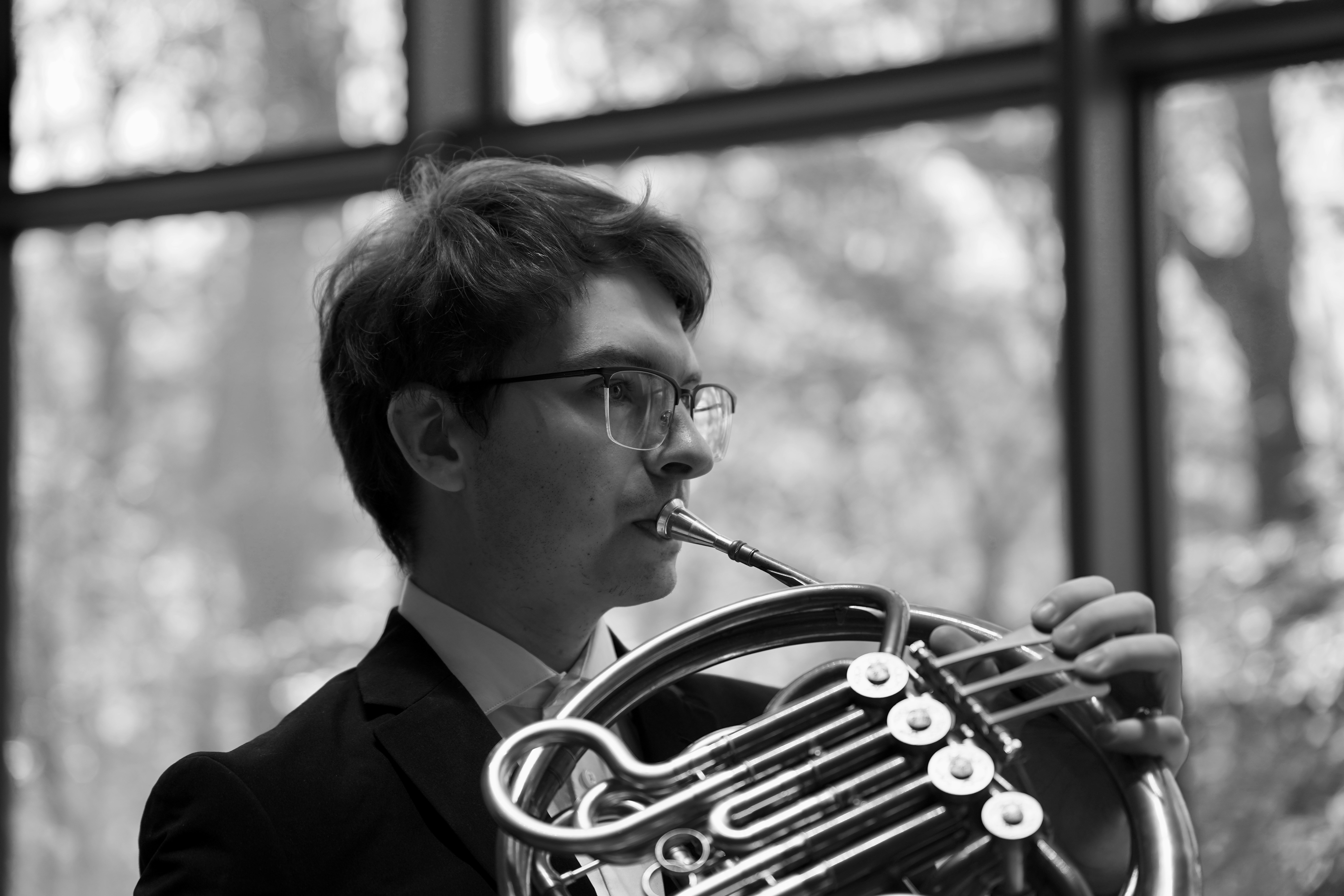 Young man playing the french horn indoors