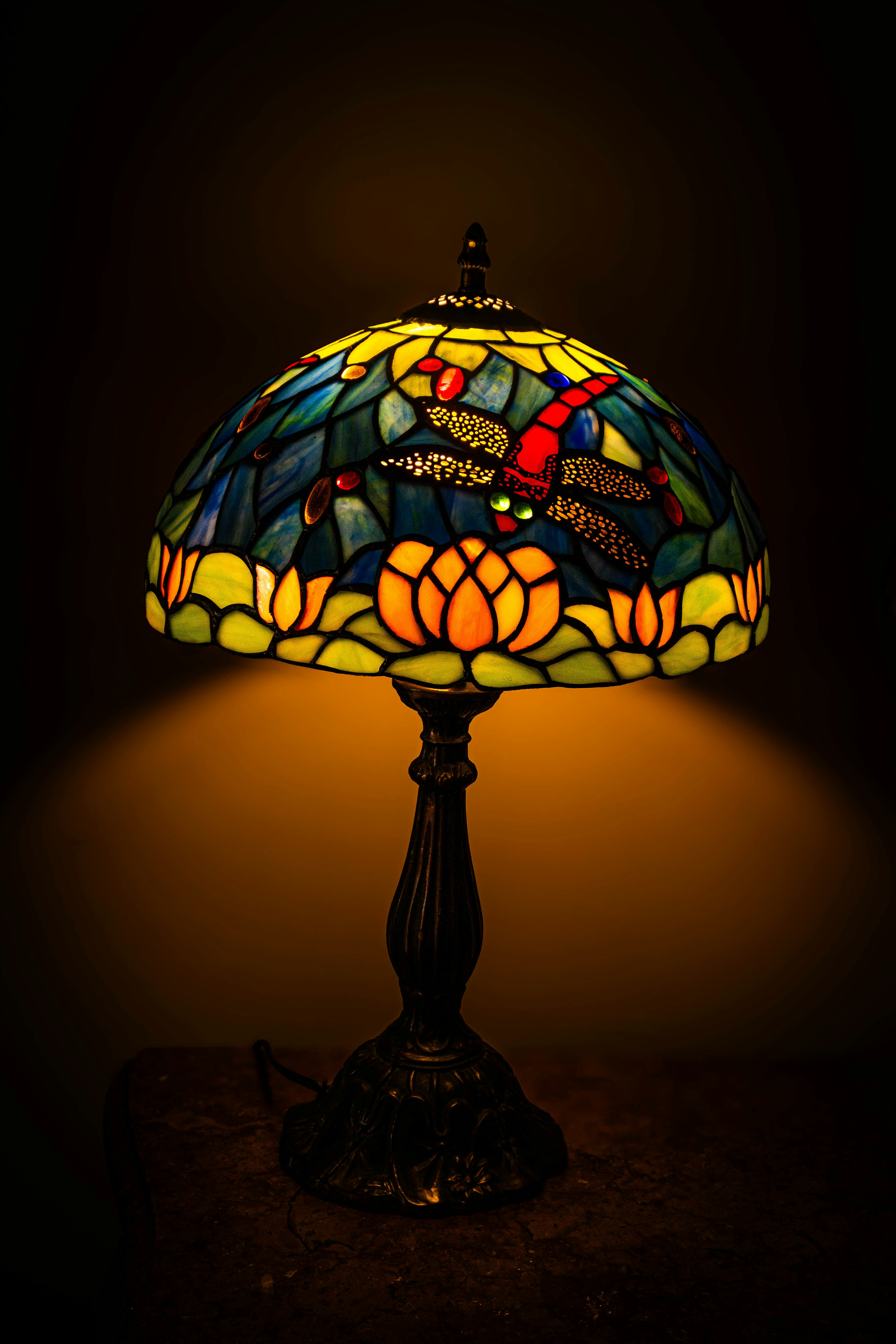 A tiffany-style lamp with dragonfly and floral motifs.