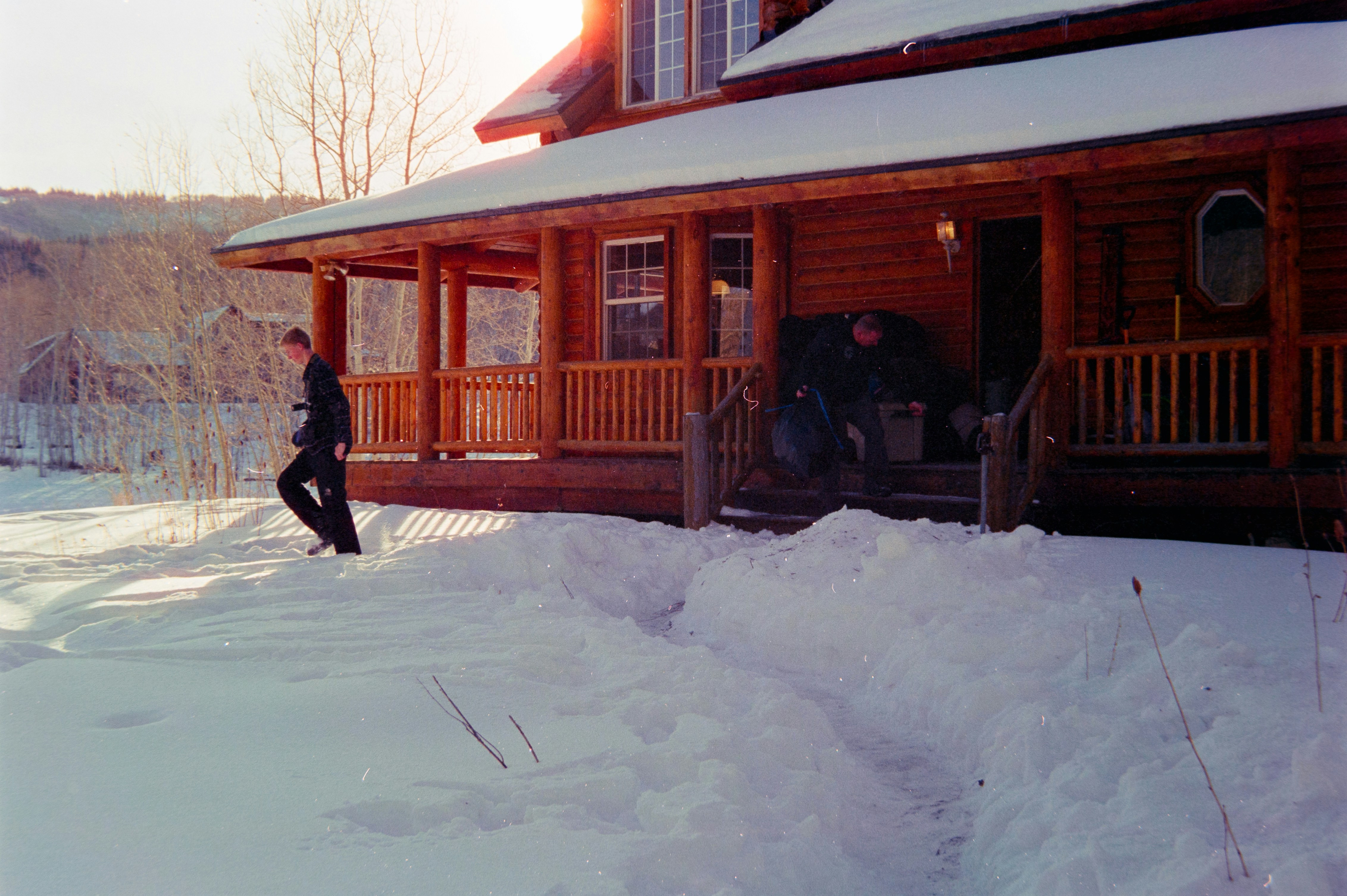 Man walking on snow path to wooden house